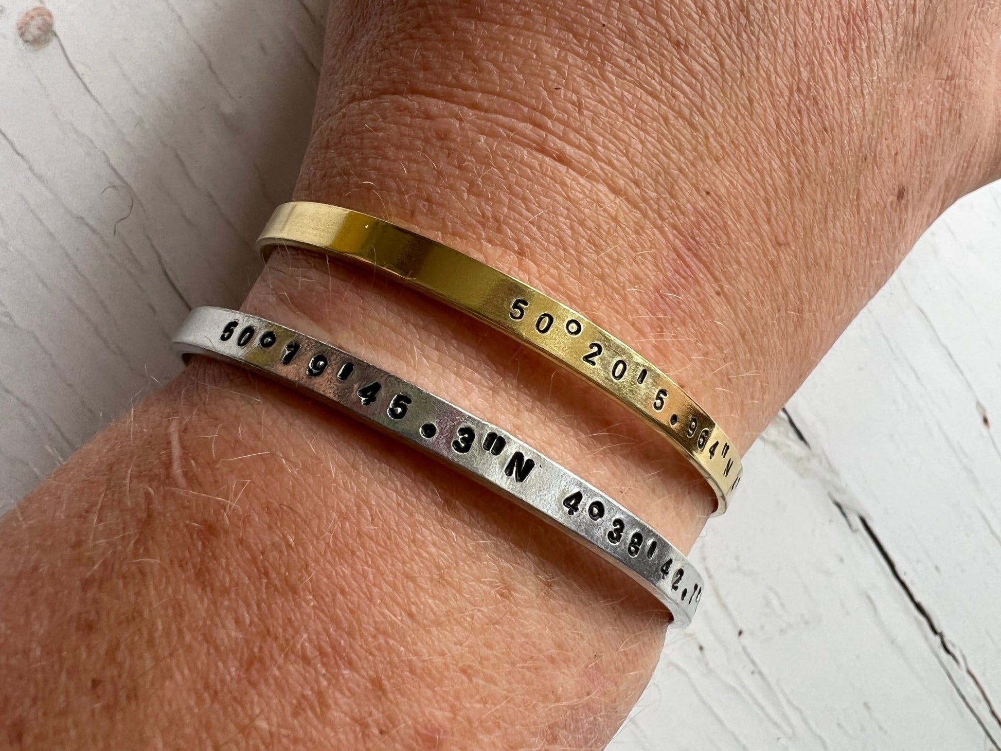 stamped coordinate cuffs on wrist, dual metal bangles brass aluminum, personalized location jewelry stack, boho style