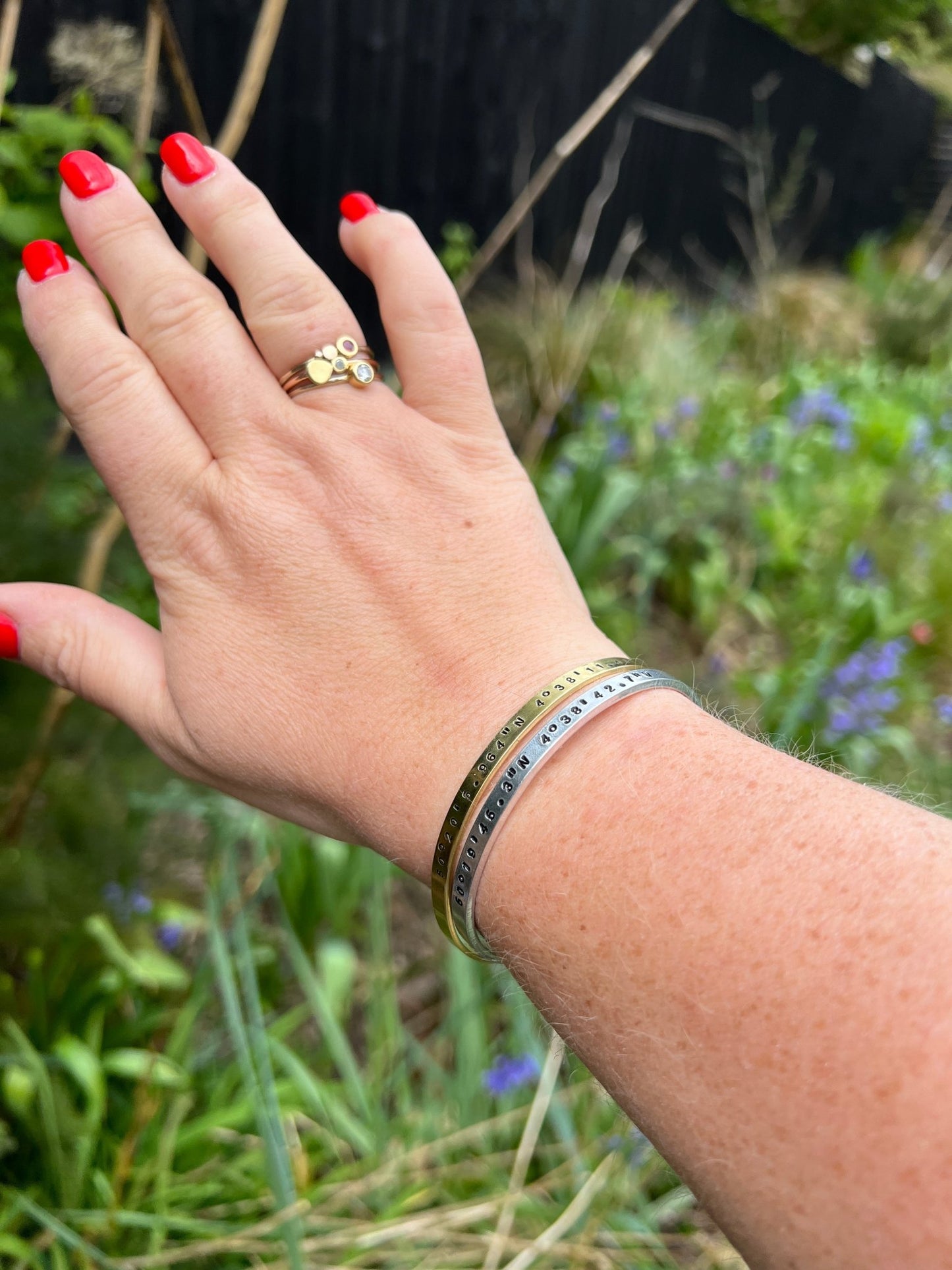 coordinates cuff bracelets worn outdoors, brass silver GPS jewelry, garden setting stamped bangles, nature photography