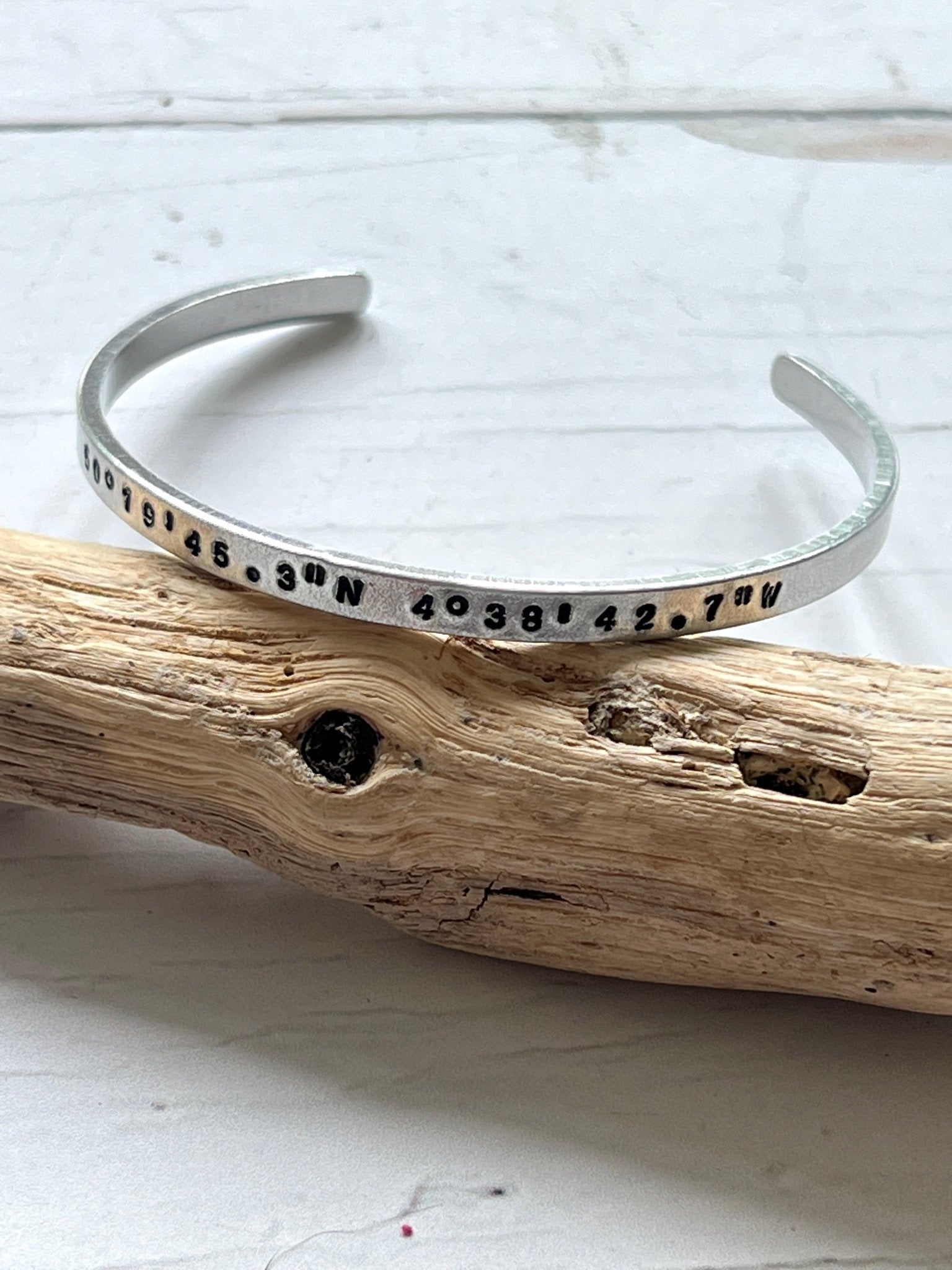 aluminum coordinates cuff bracelet on driftwood, stamped jewelry, personalized location bangle, coastal minimalist style
