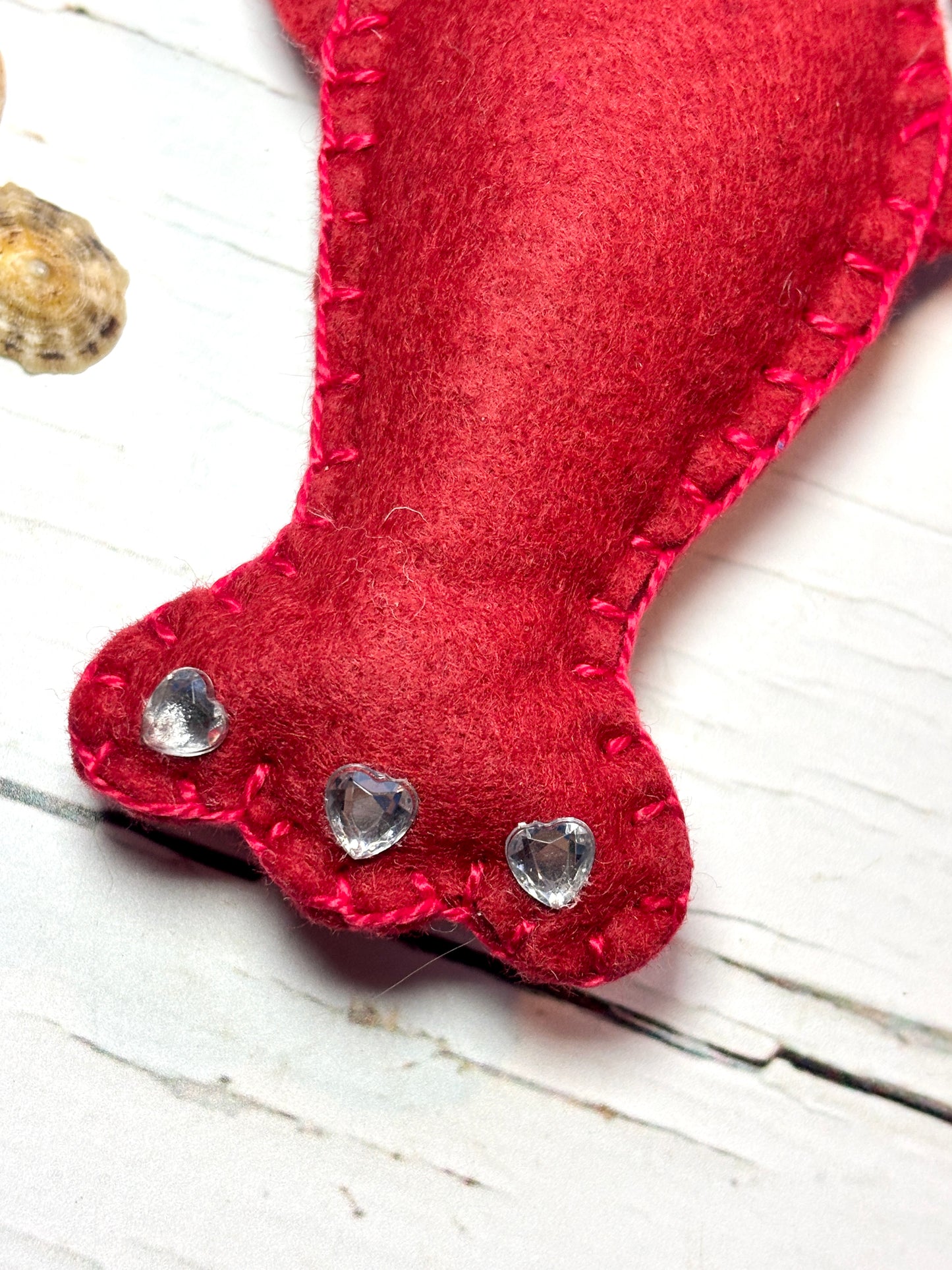closeup shot of red felt lobster tail handstitched craft detail with three heart-shaped rhinestones unique coastal Christmas decor