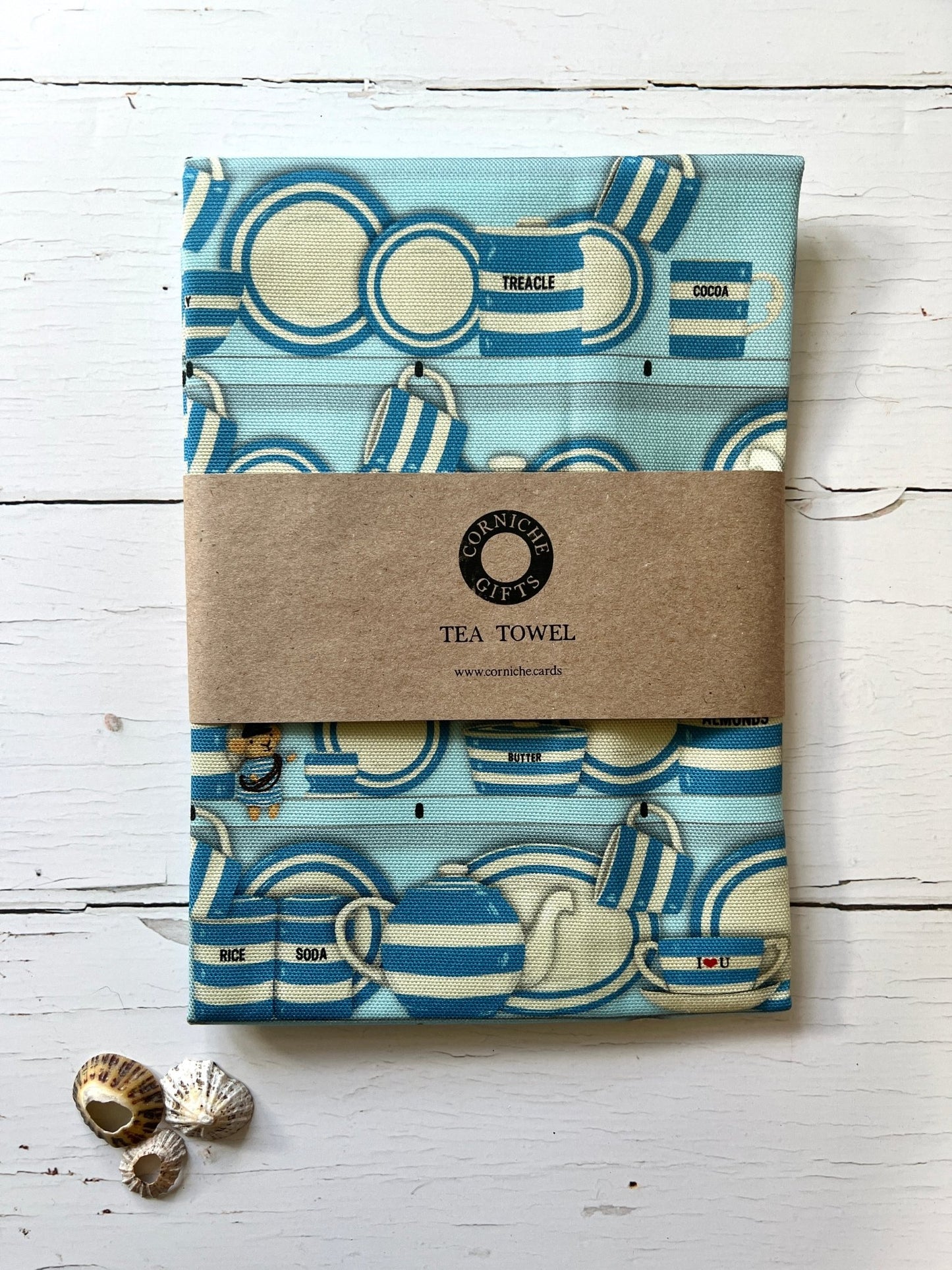 corniche gifts sky blue tea towel featuring striped Cornish crockery pattern, kraft paper band, seashell accents