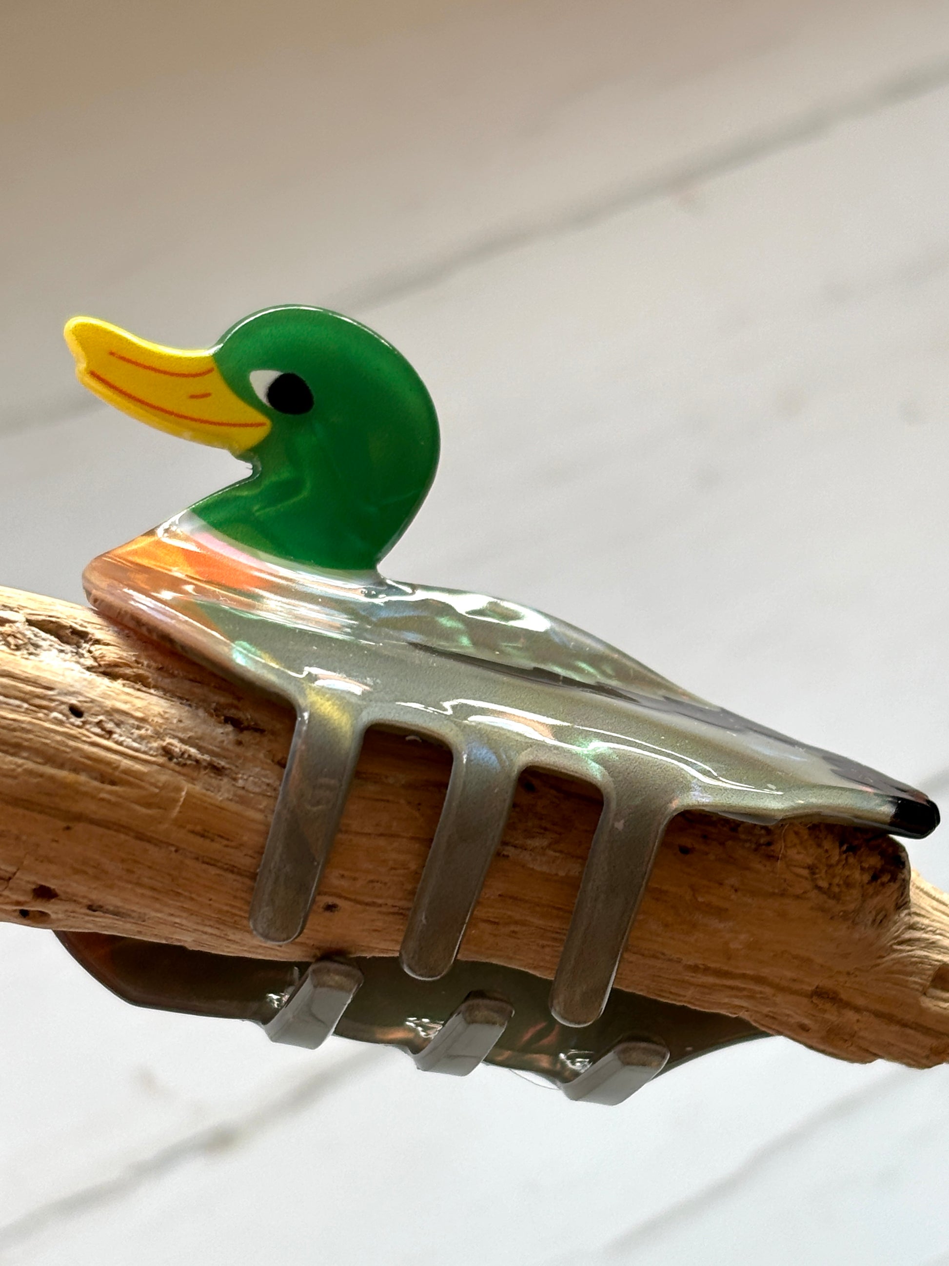 closeup shot of glossy duck hair claw clip with green head and yellow beak, retro animal accessory with iridescent finish