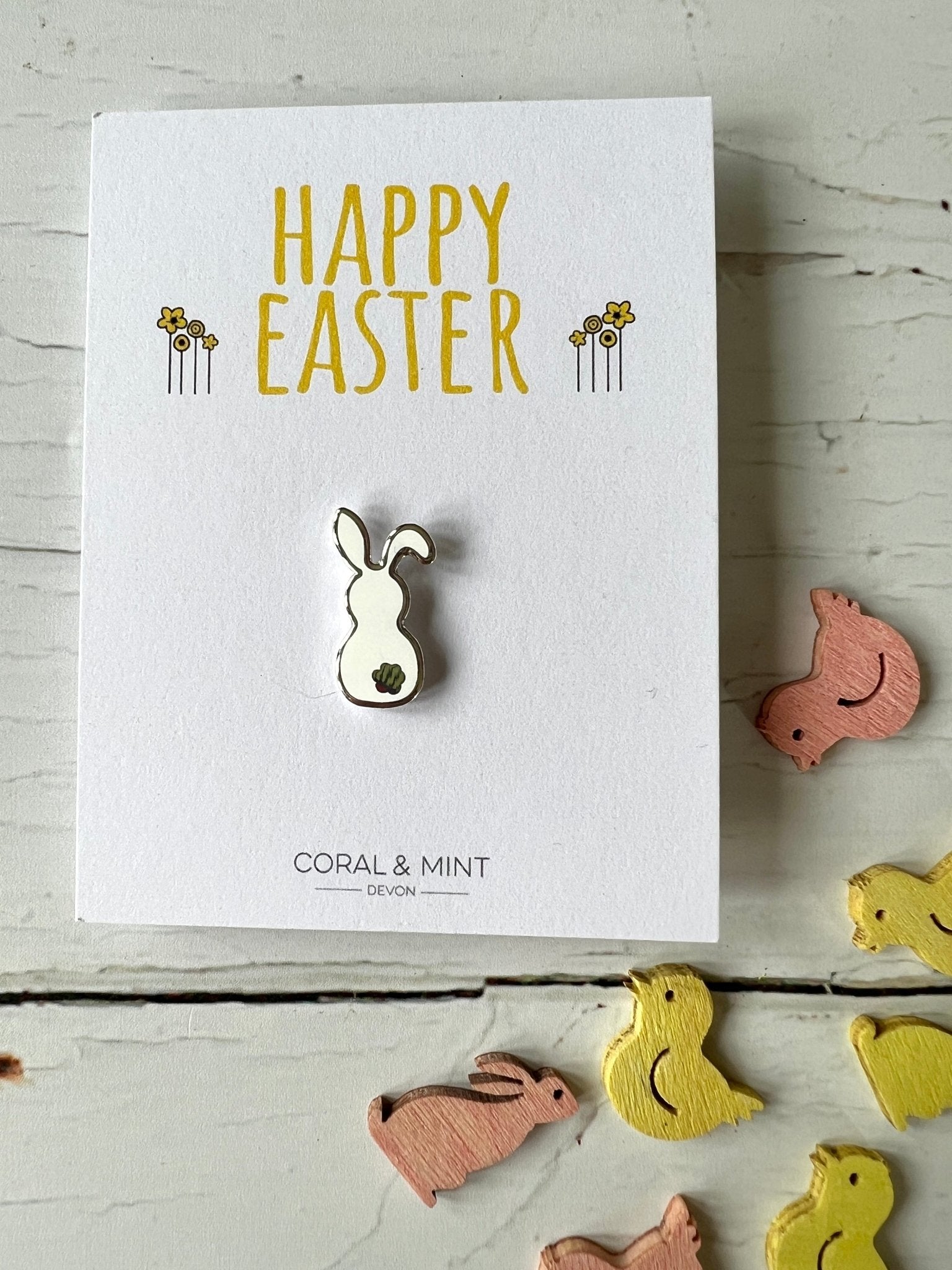 white easter bunny enamel pin badge on Happy Easter greeting card with wooden chick and bunny decorations