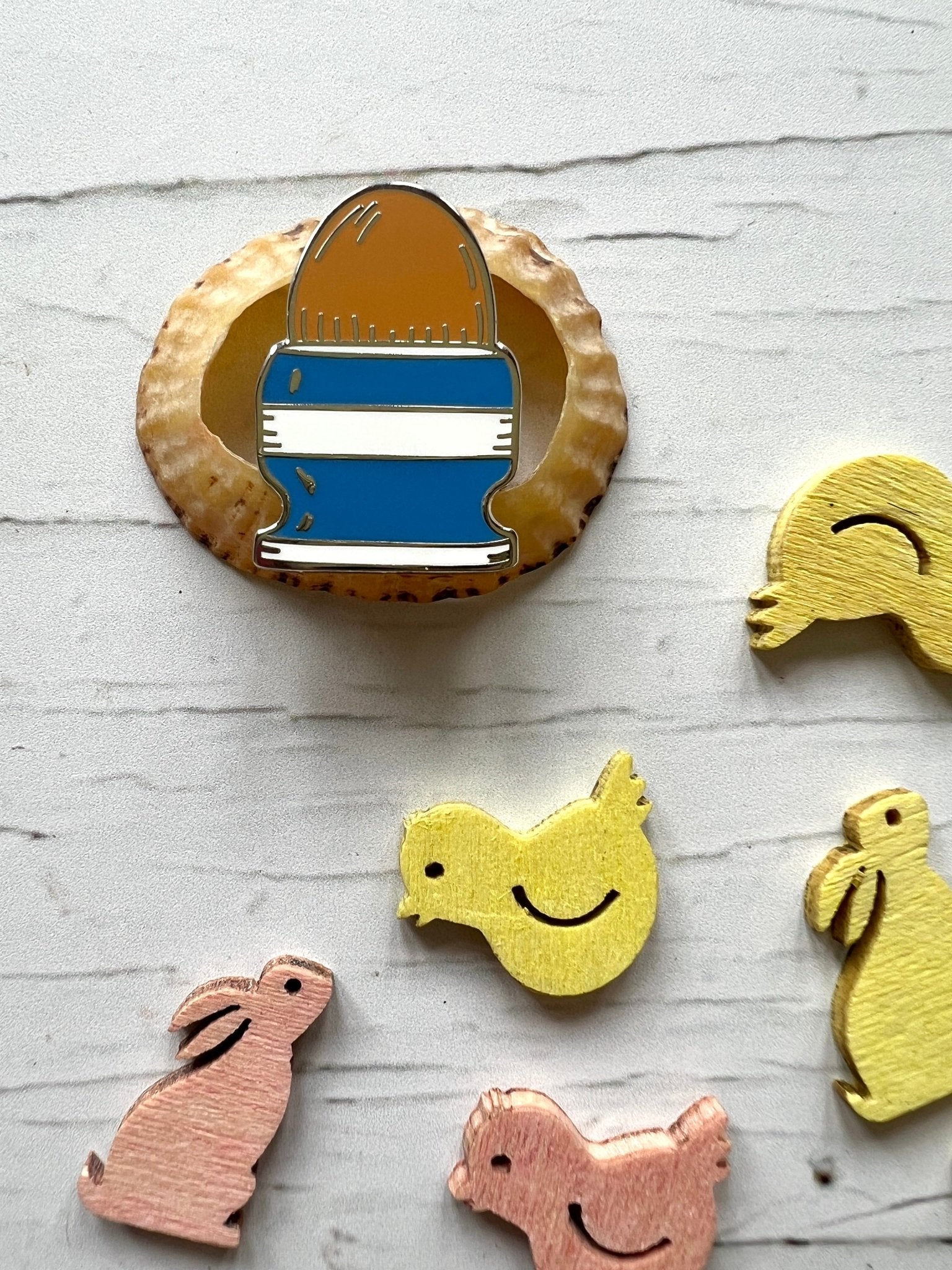 Cornish blue striped easter egg in egg cup enamel pin badge on shell with wooden spring animal decorations