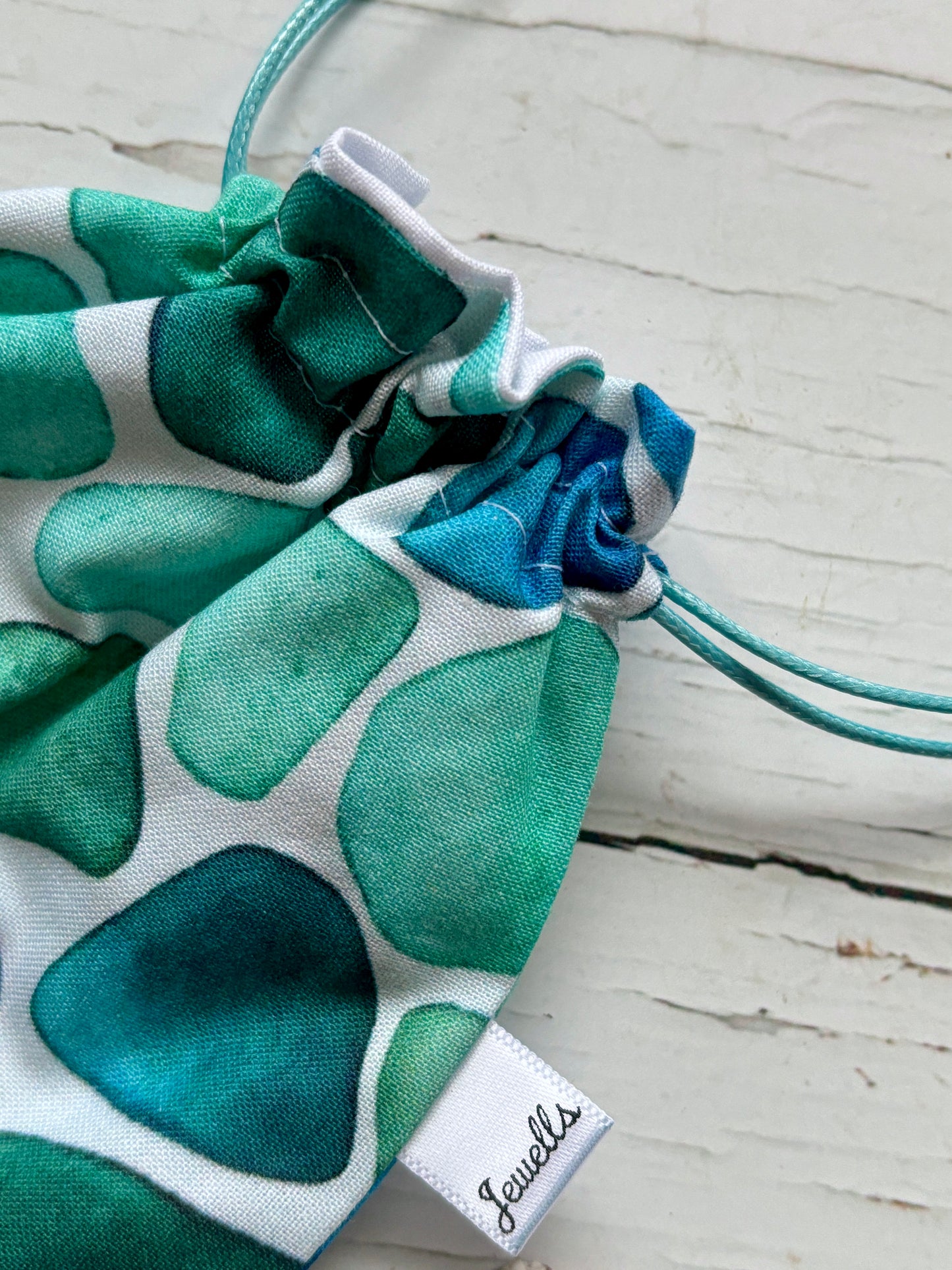 close up of the drawstring detail on a small fabric bag with a sea glass print