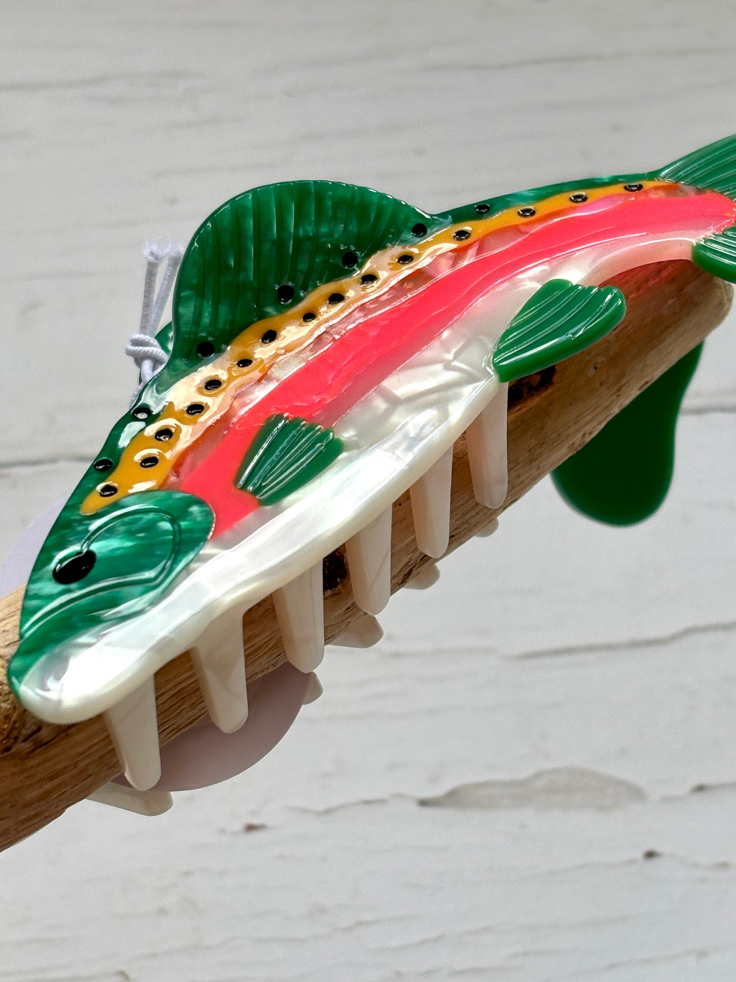 closeup shot of fish hair claw—iridescent trout design with secure grip, playful aquatic style, and glossy everyday finish