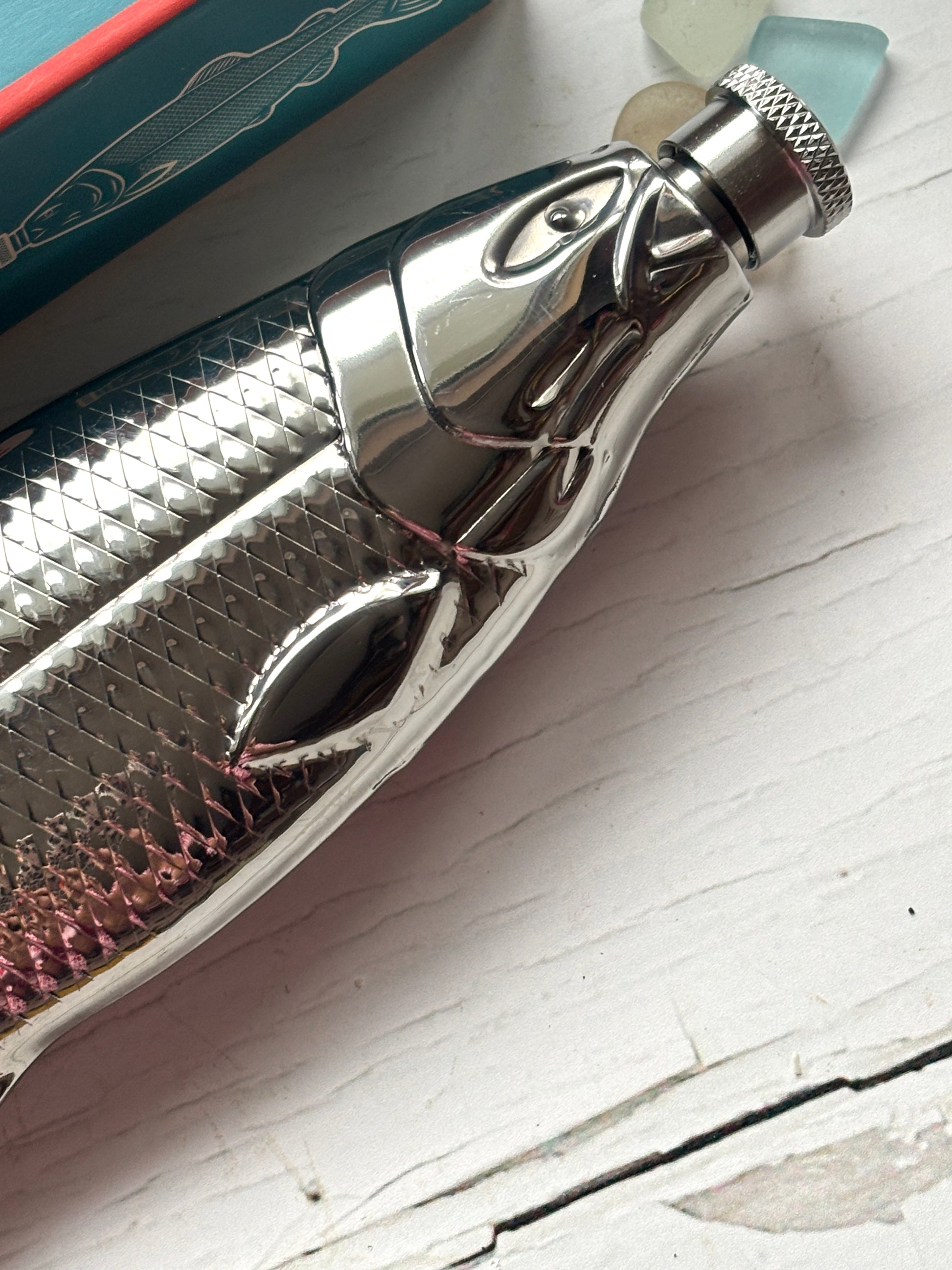 fish flask closeup showing textured scale detail and screw cap, chrome stainless steel novelty hip flask head design