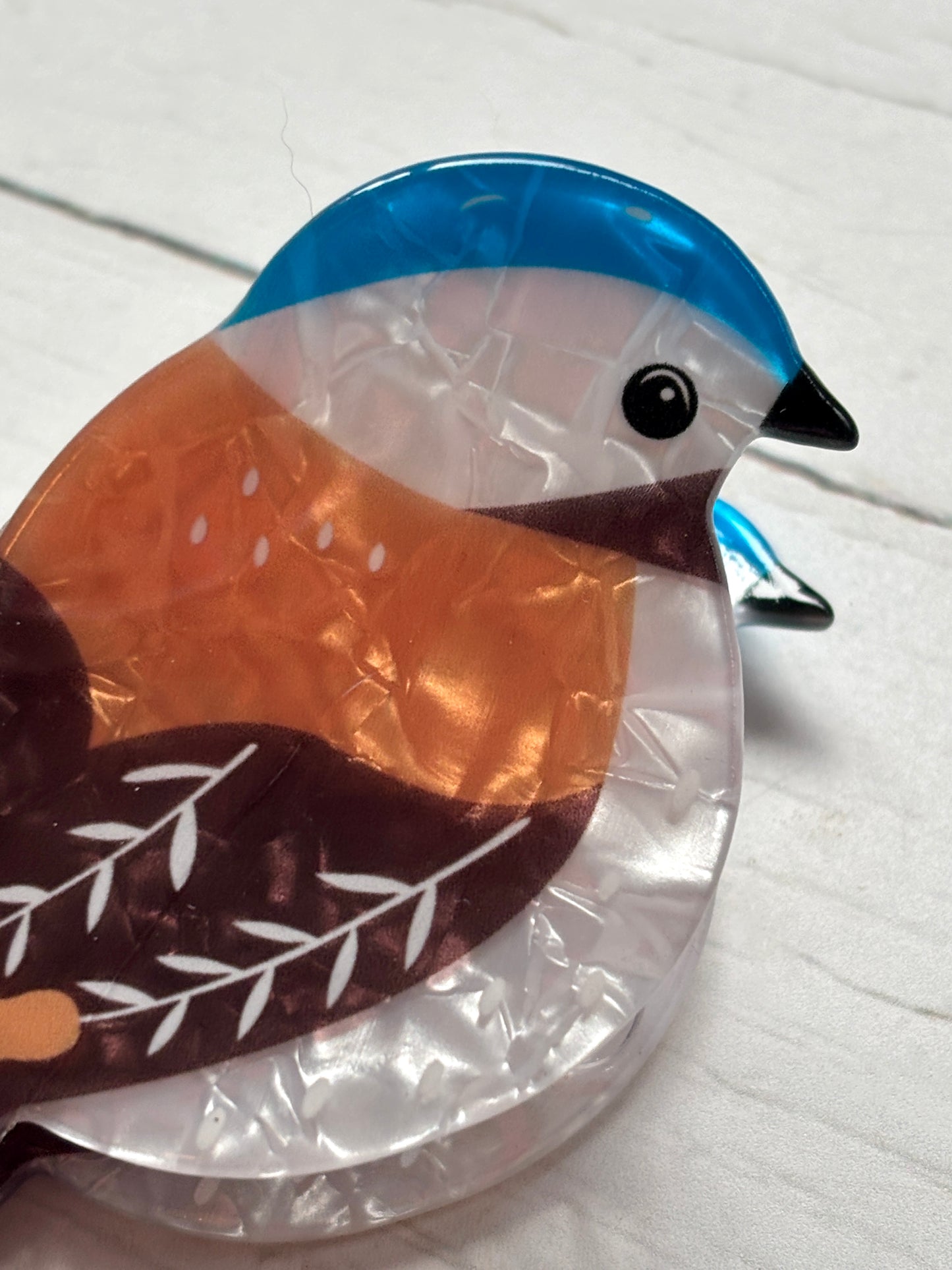 closeup shot of a bluebird hair claw clip, featuring a bright blue and orange marbled acrylic design trendy spring hair accessory
