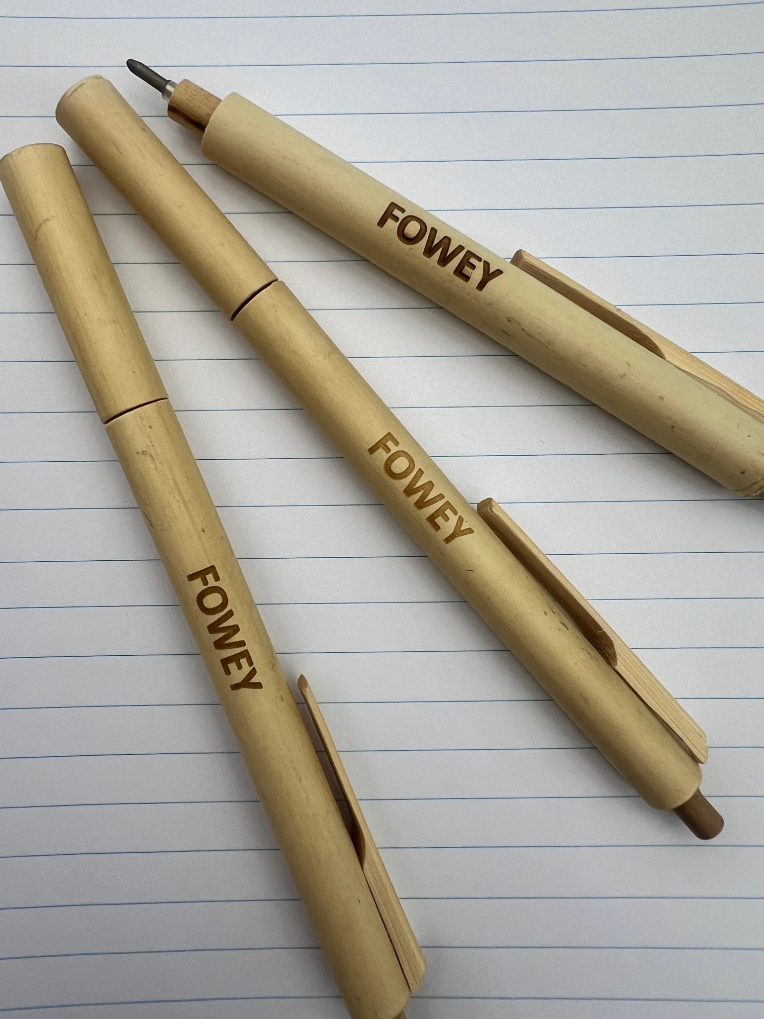 closeup shot of engraved Fowey bamboo pens, natural wood grain ballpoint, sustainable Cornwall souvenir, eco writing tools