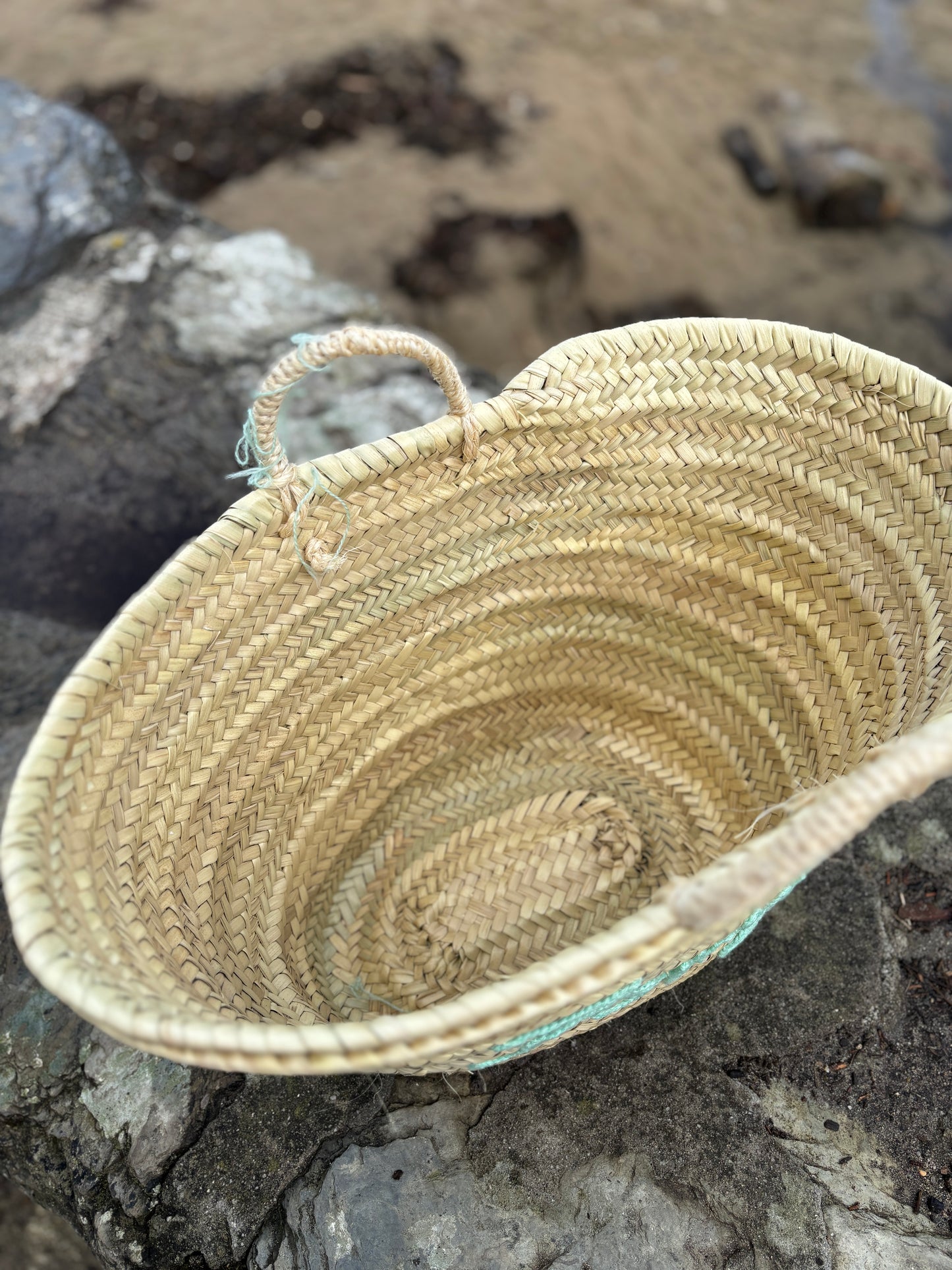an inside view of a hand-woven straw maxi basket bag shows the natural texture of the large beach tote or coastal market bag interior