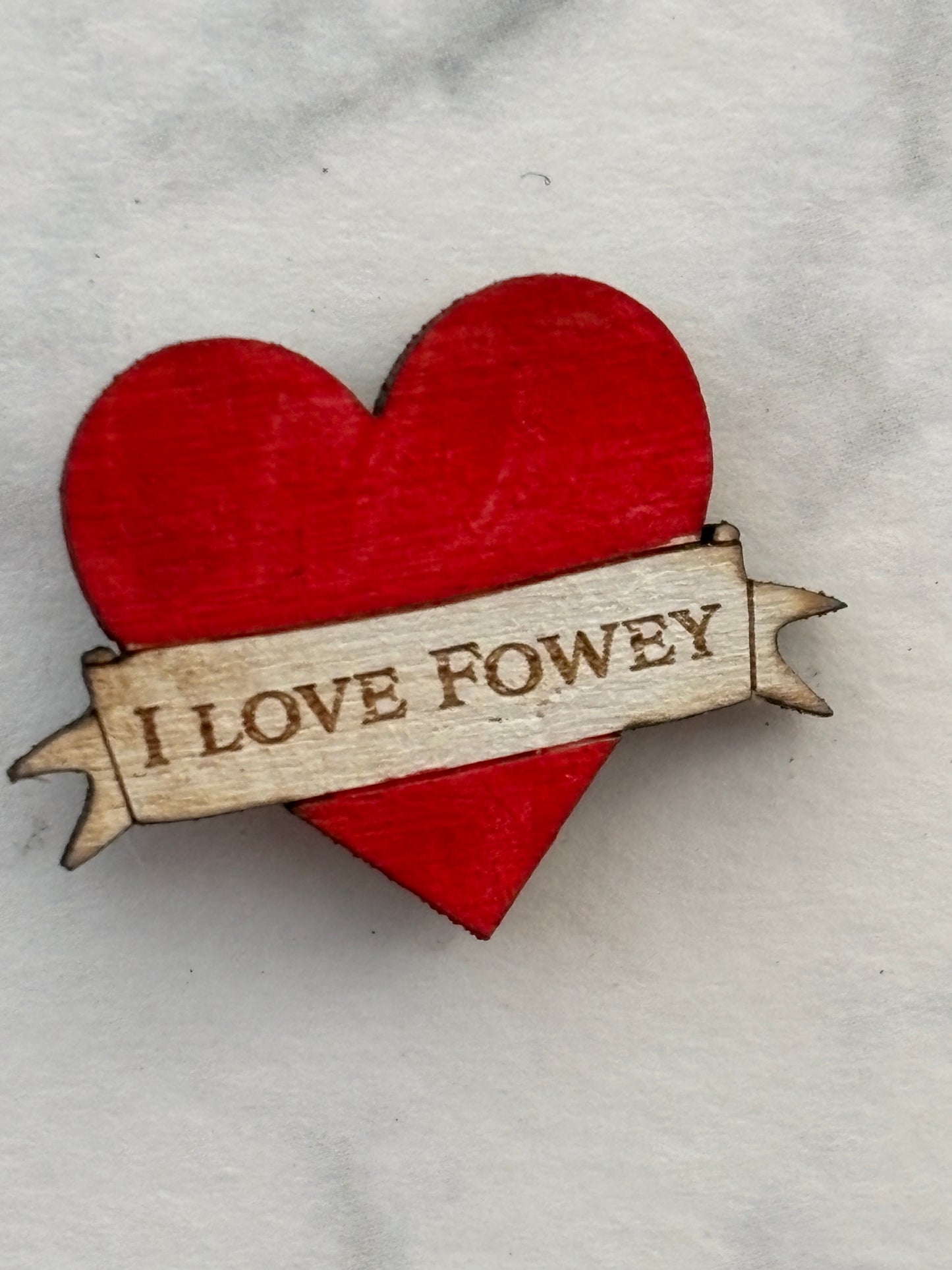 closeup shot of red heart-shaped wooden pin badge with “I LOVE ROWEY” engraving—handmade, rustic, sentimental keepsake gift
