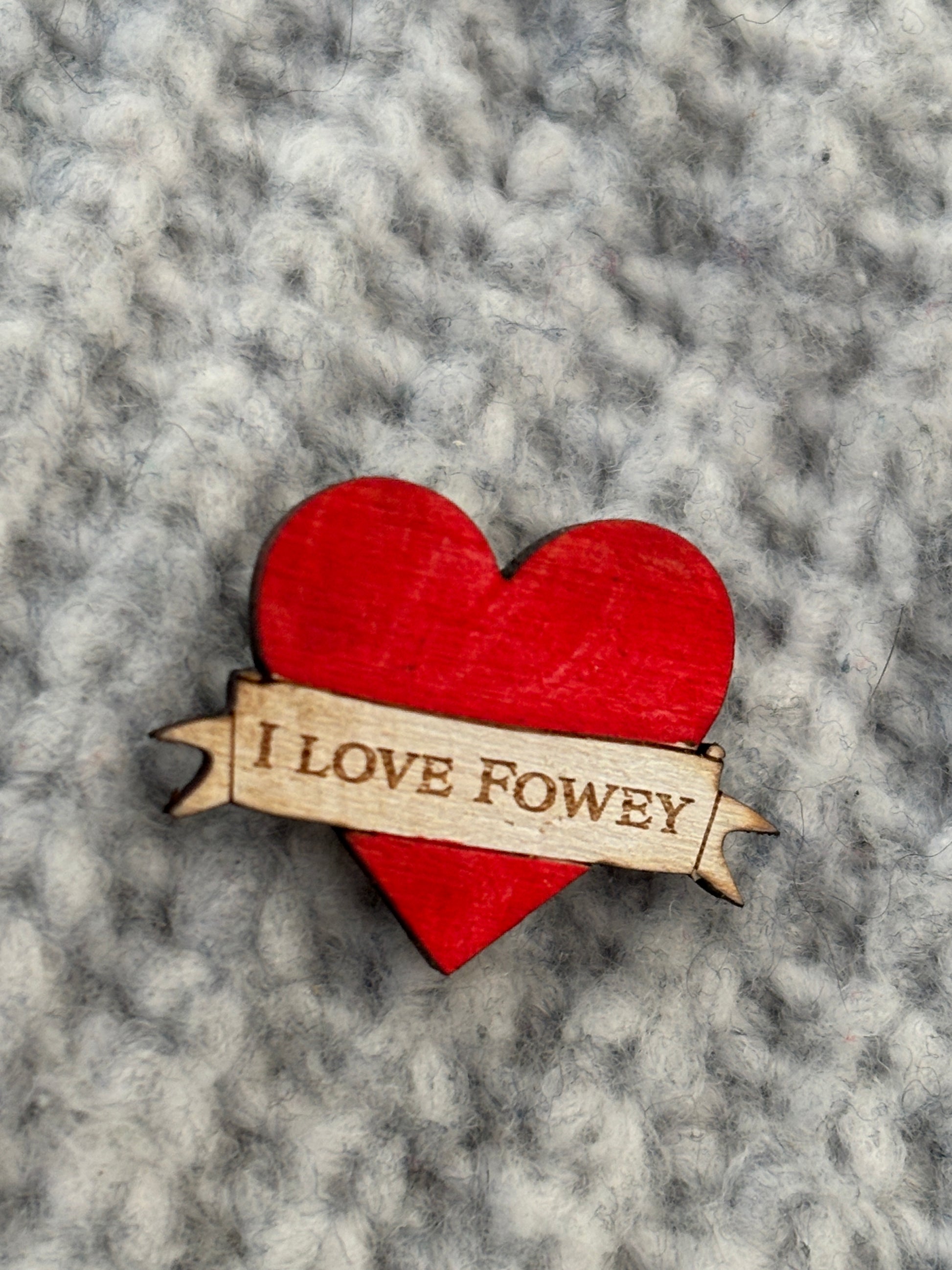 closeup shot of handmade red heart wooden pin badge with “I LOVE FOWEY” engraving—eco-friendly coastal keepsake gift
