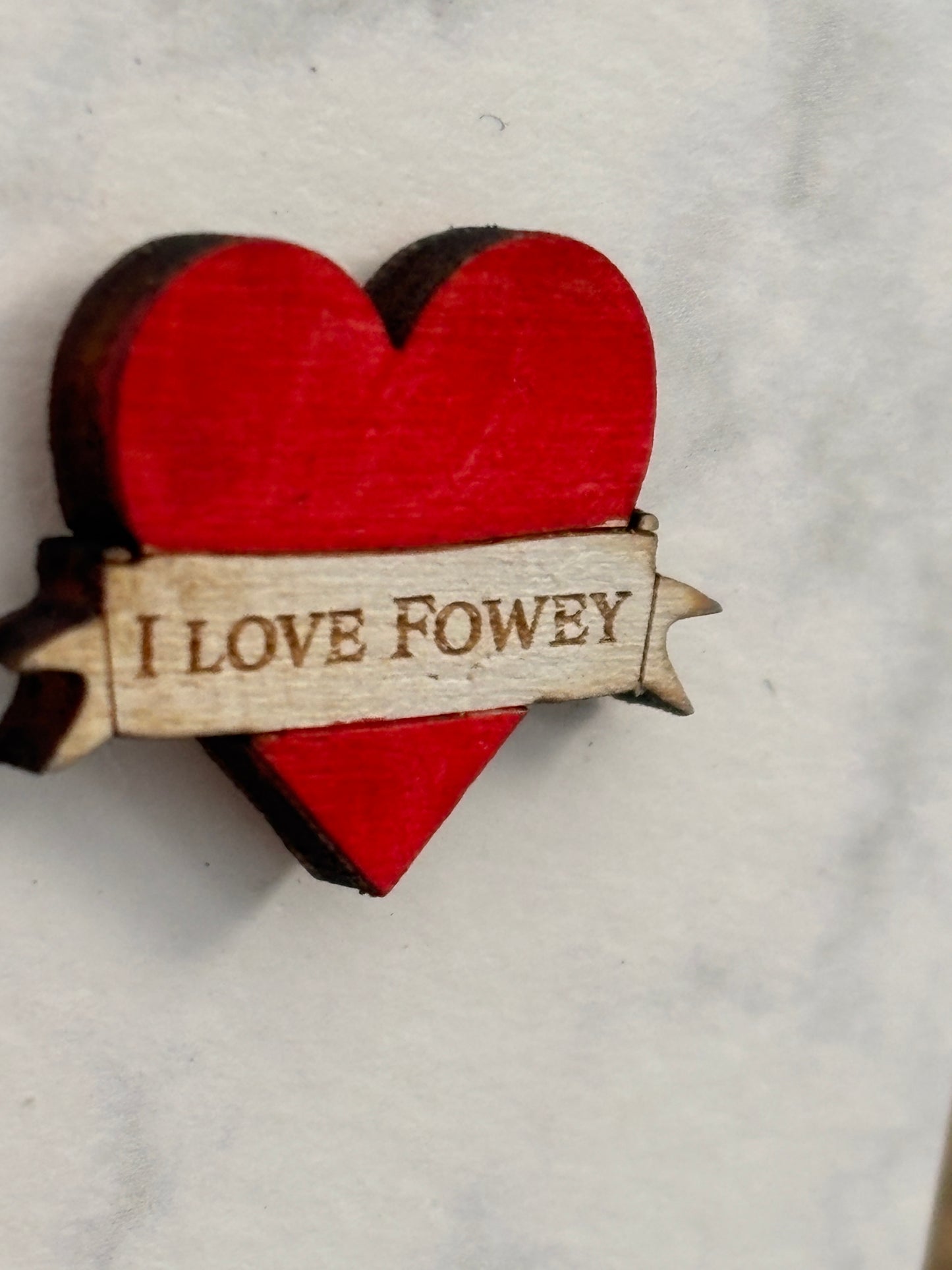 side view of red heart-shaped wooden pin badge with “I LOVE FOWEY” engraving—handmade, eco-friendly coastal souvenir