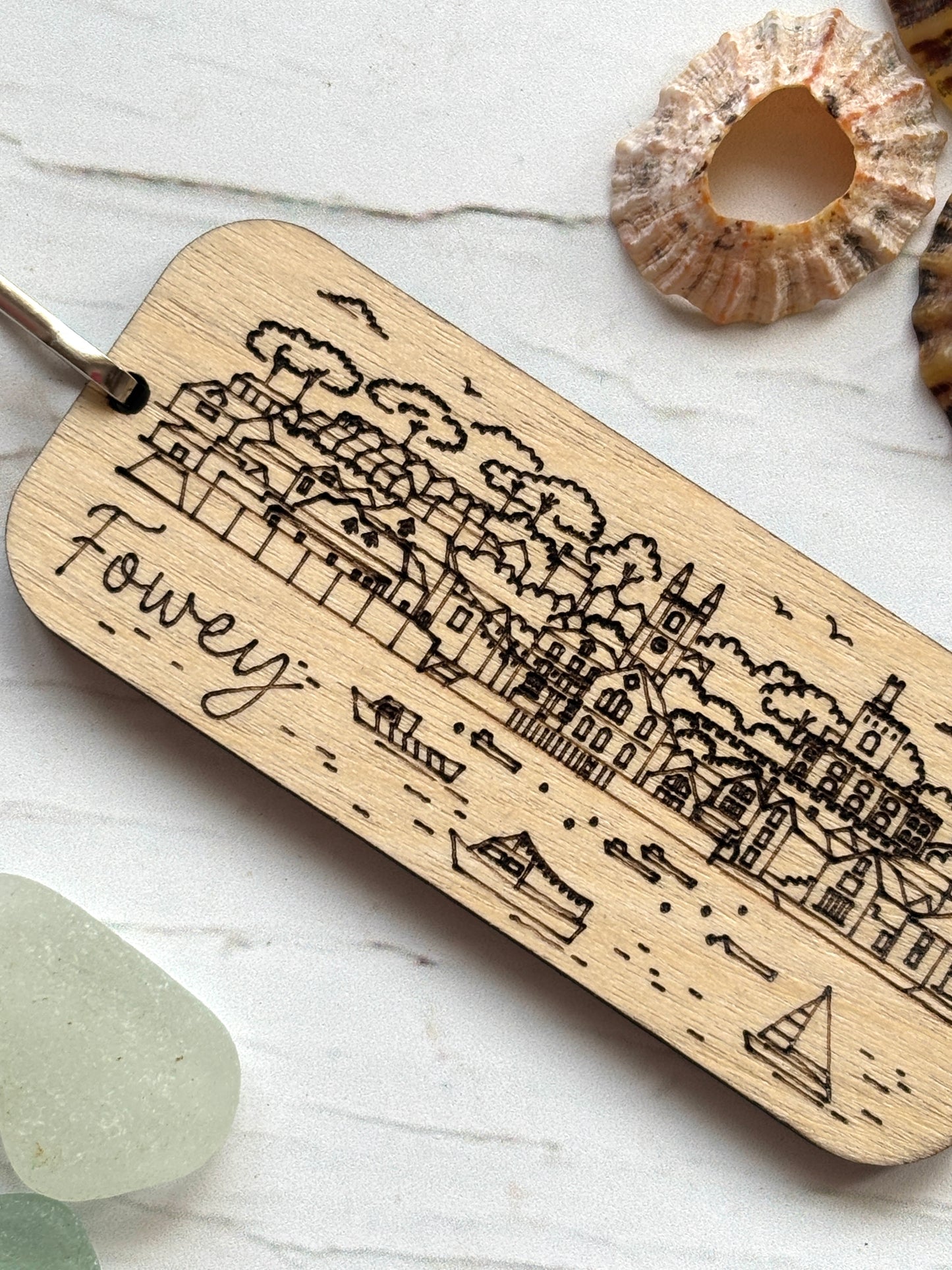Fowey wooden keychain detail, engraved Cornwall town harbor scene, laser etched coastal buildings, wood grain texture