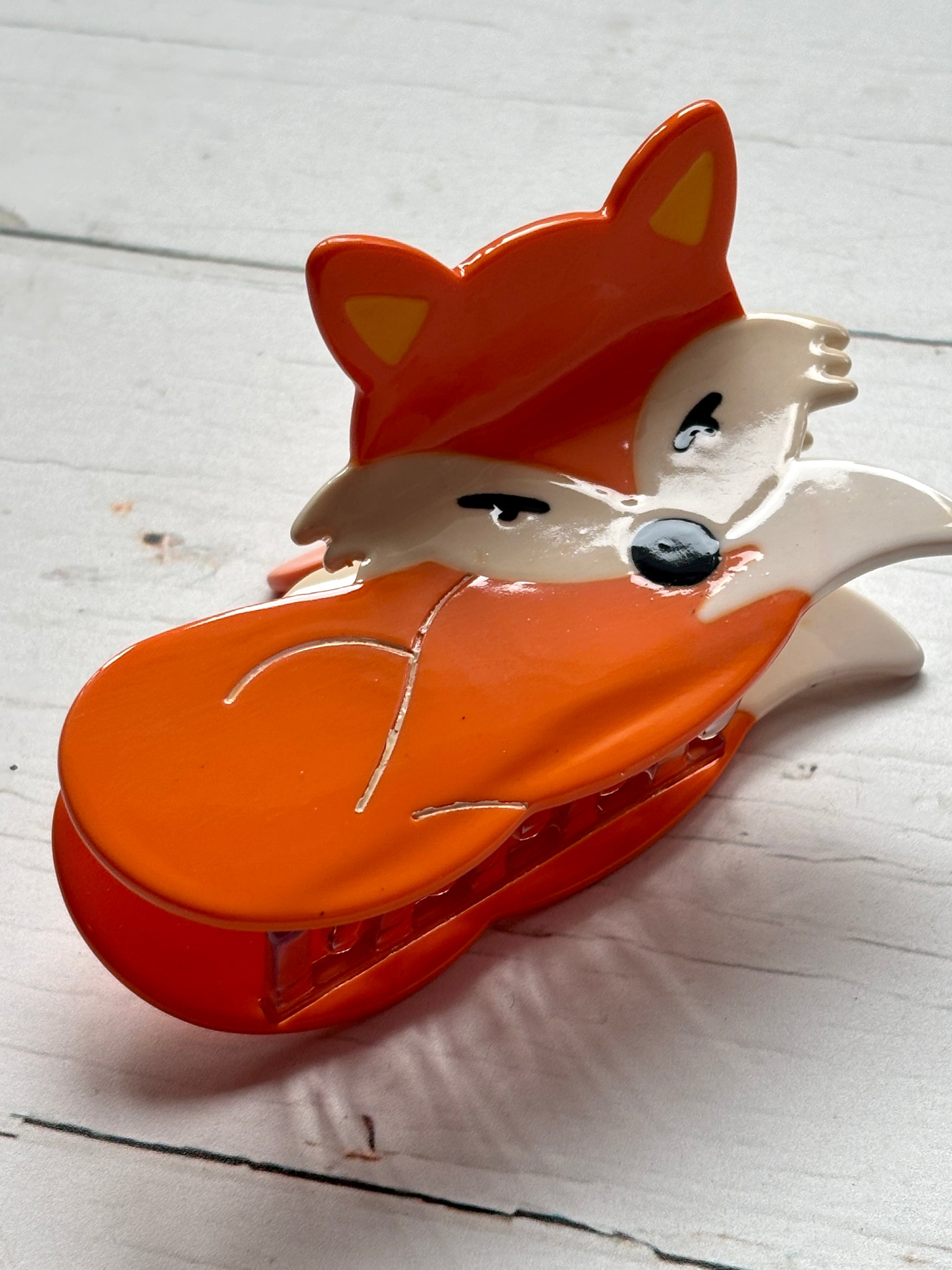 lifestyle shot of fox hair claw—glossy orange clip with sly eyes, white accents, and secure grip for playful woodland styling