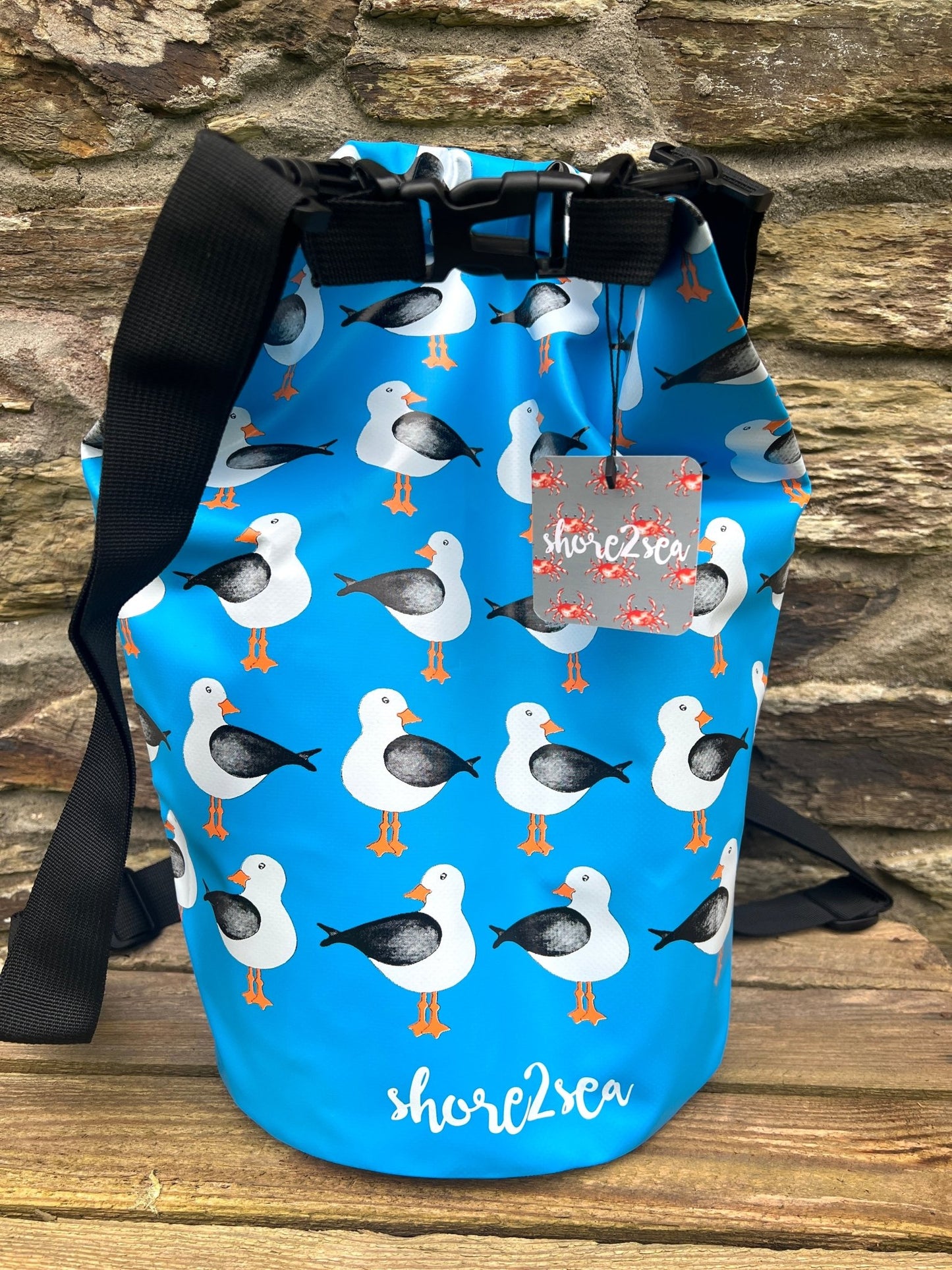 blue waterproof dry bag featuring a funky nautical pattern of repeating seagull graphics essential beach gear for water sports.
