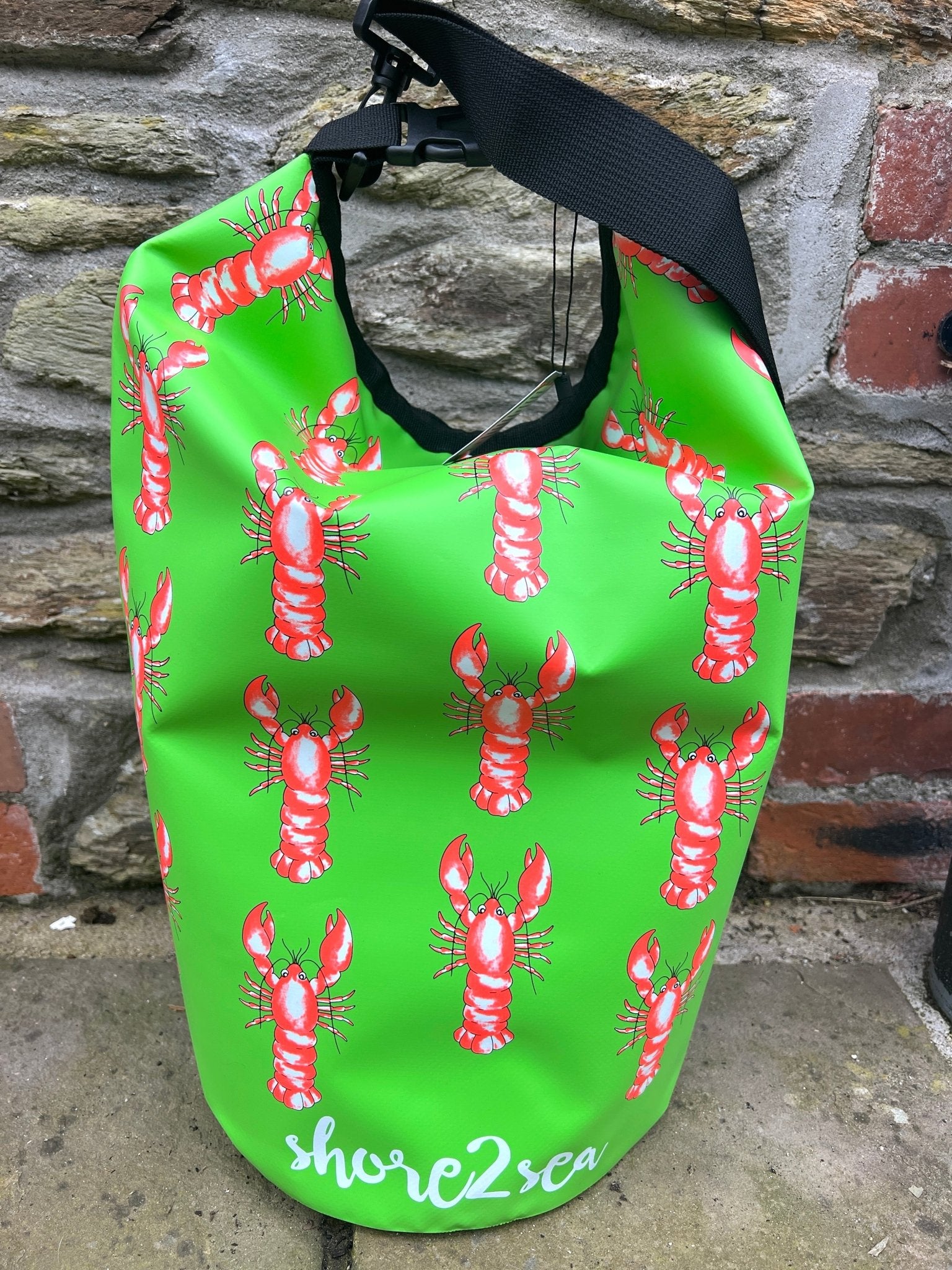 green waterproof dry bag featuring a funky nautical pattern of repeating red lobster graphics ideal for beach and watersports