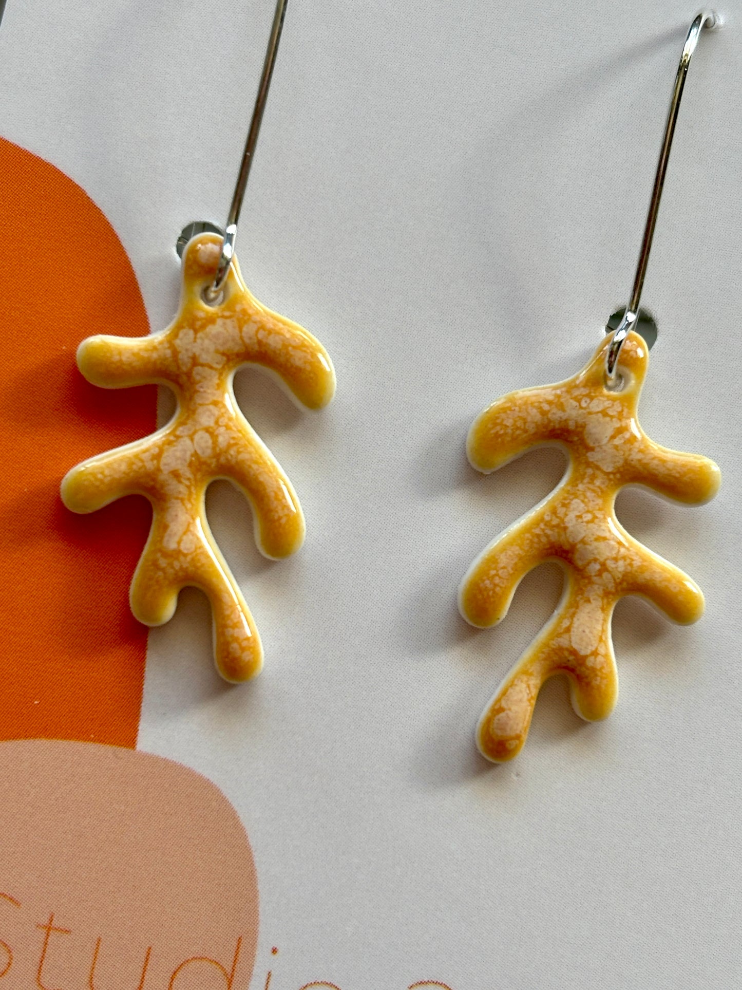 closeup shot of glazed porcelain drop earrings – marbled orange ceramic dangles with coral-inspired shape, lightweight and handmade