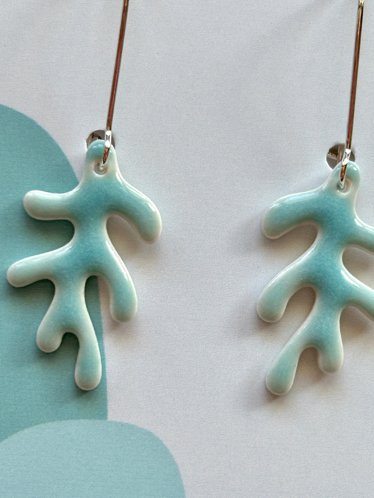 closeup shot of glazed porcelain drop earrings – turquoise coral-inspired ceramic dangles, lightweight, artisanal, and ocean-toned