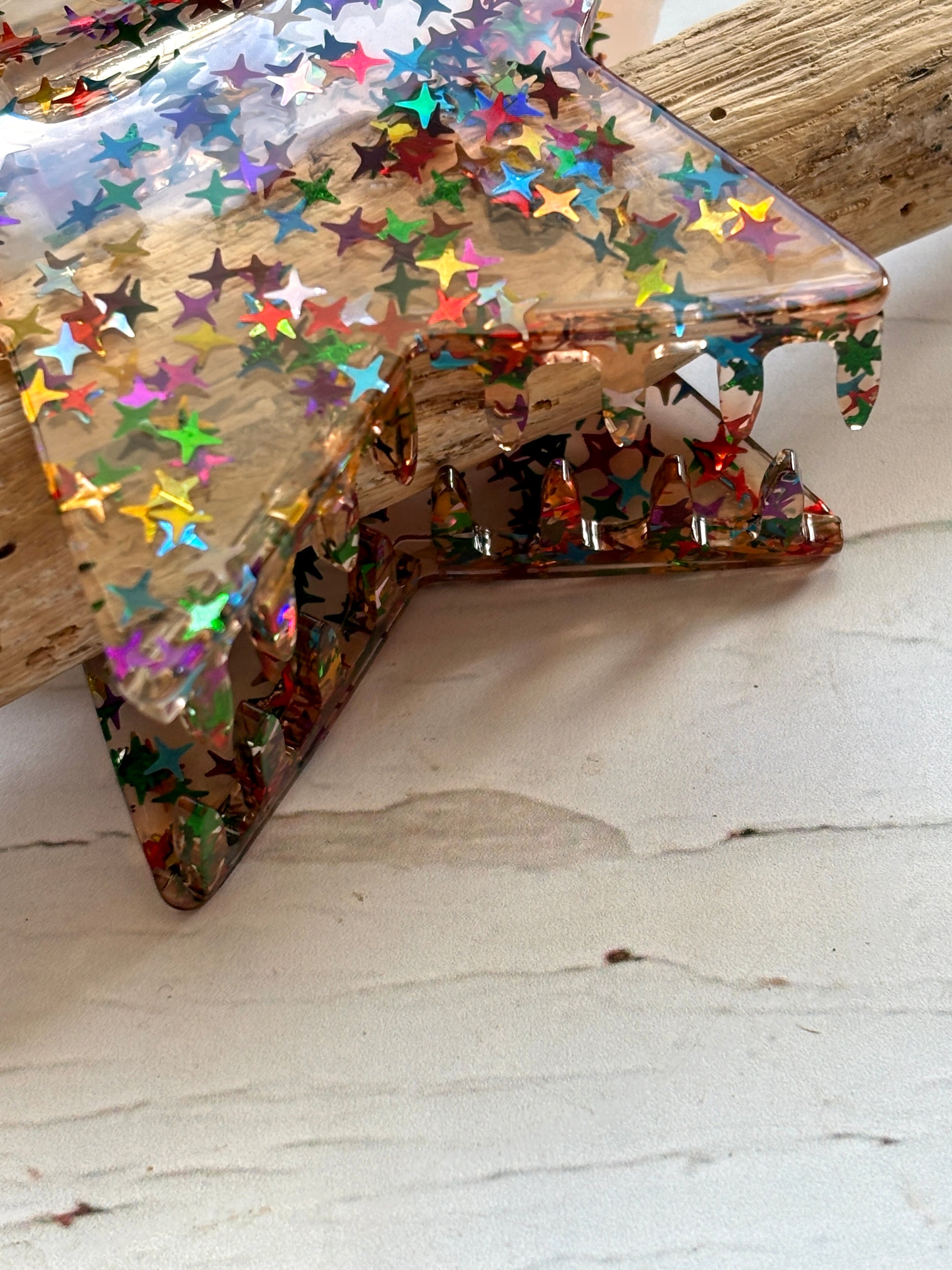 closeup shot glitter star hair claw—clear clip with festive confetti, glossy finish, and secure celestial-inspired grip