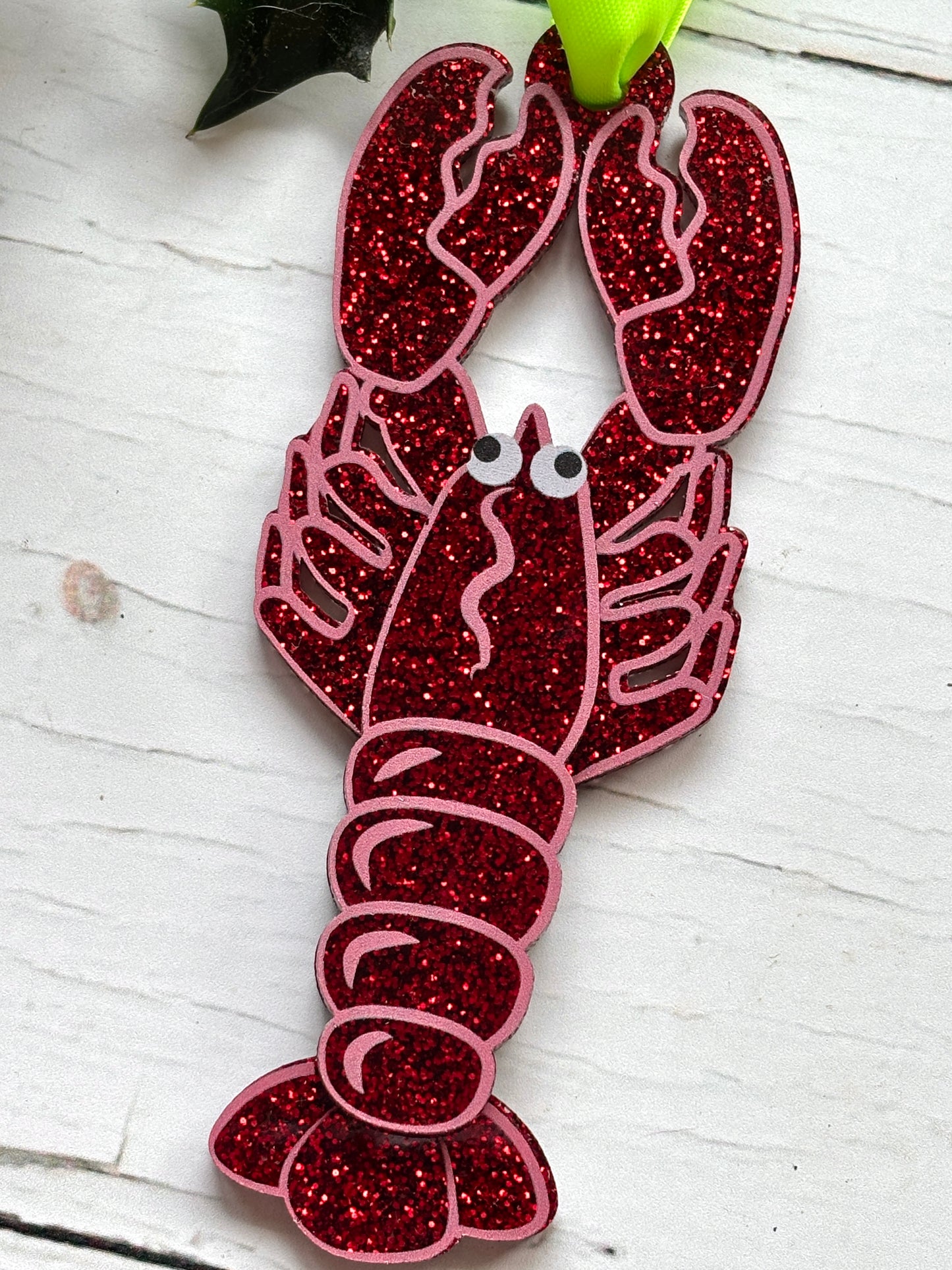 glittery lobster Christmas decor—red glitter ornament with cartoon eyes and green ribbon, perfect for coastal holiday styling