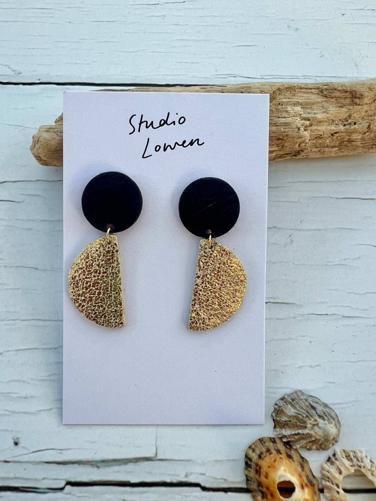 gold and black half-moon drop earrings made from textured polymer clay handmade jewellery with a modern geometric and statement style