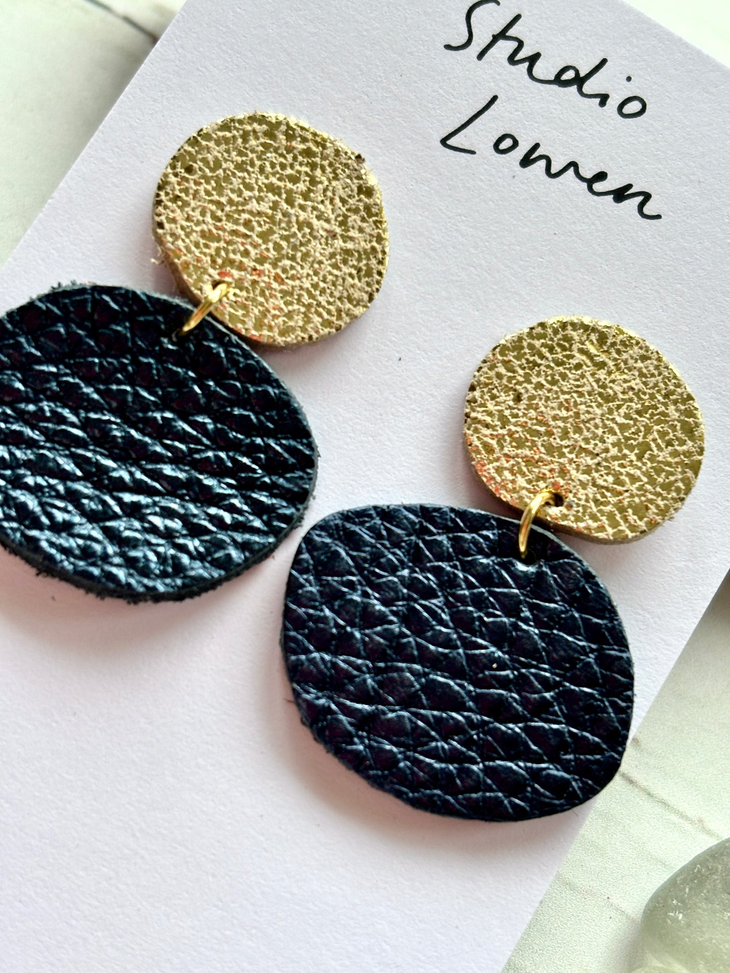closeup shot of gold textured stud and metallic navy blue dangle earrings handmade polymer clay statement jewelry