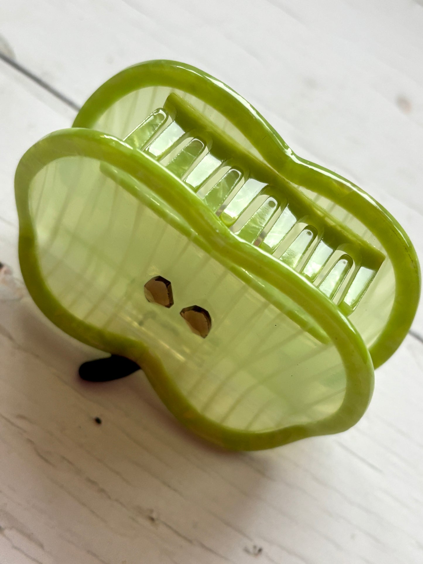 closeup shot of green apple hair claw—striped translucent body with seed accents, glossy finish, and secure grip for daily wear