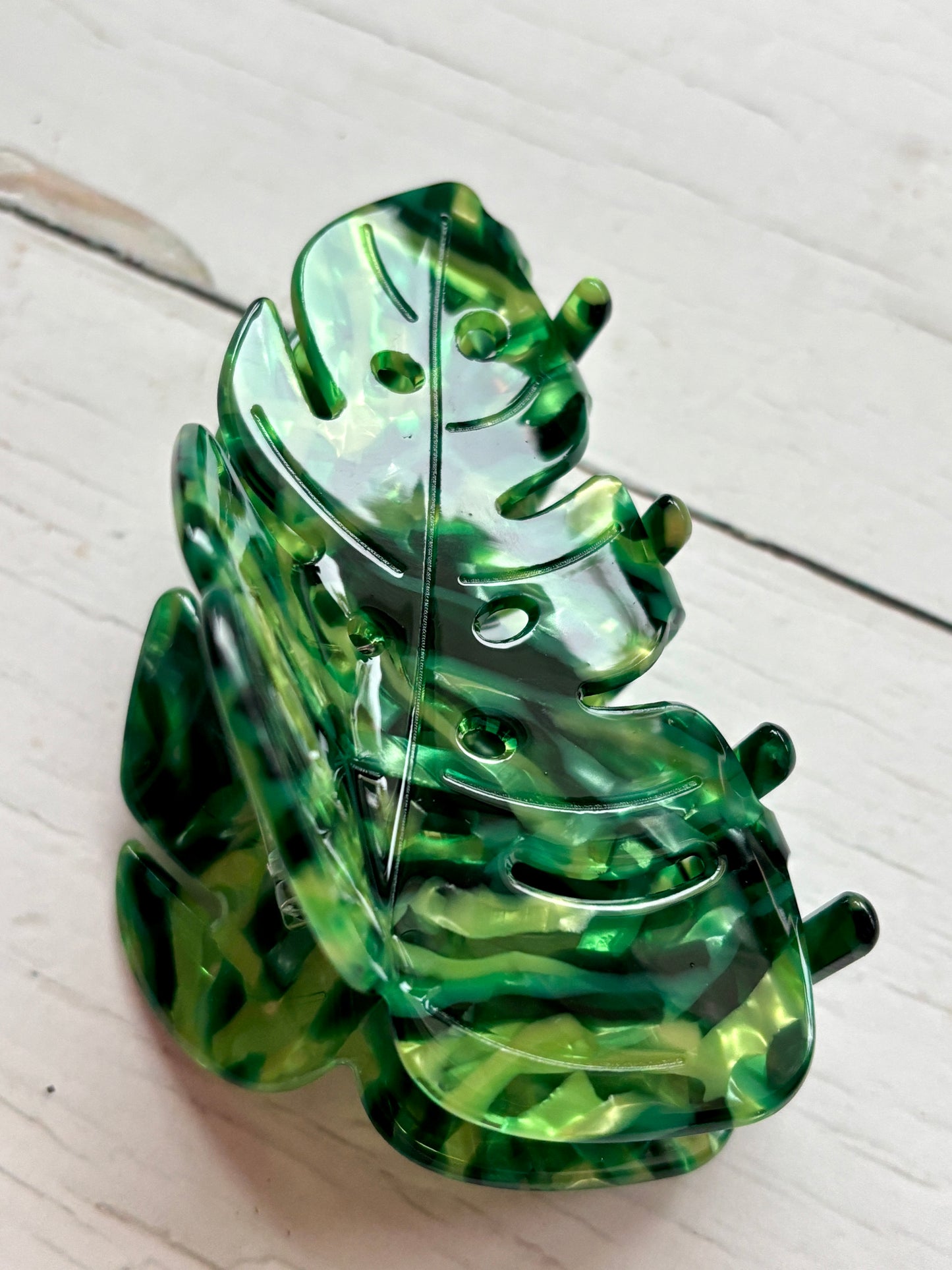 closeup shot of the bright green acrylic Monstera leaf hair claw clip, showcasing the unique tropical pattern and teeth