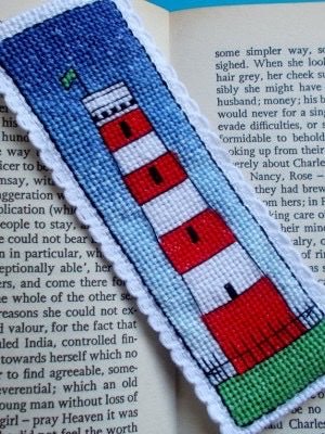 closeup shot of a finished Gribbin Daymark cross stitch bookmark handmade nautical craft with a red and white lighthouse design reading gift