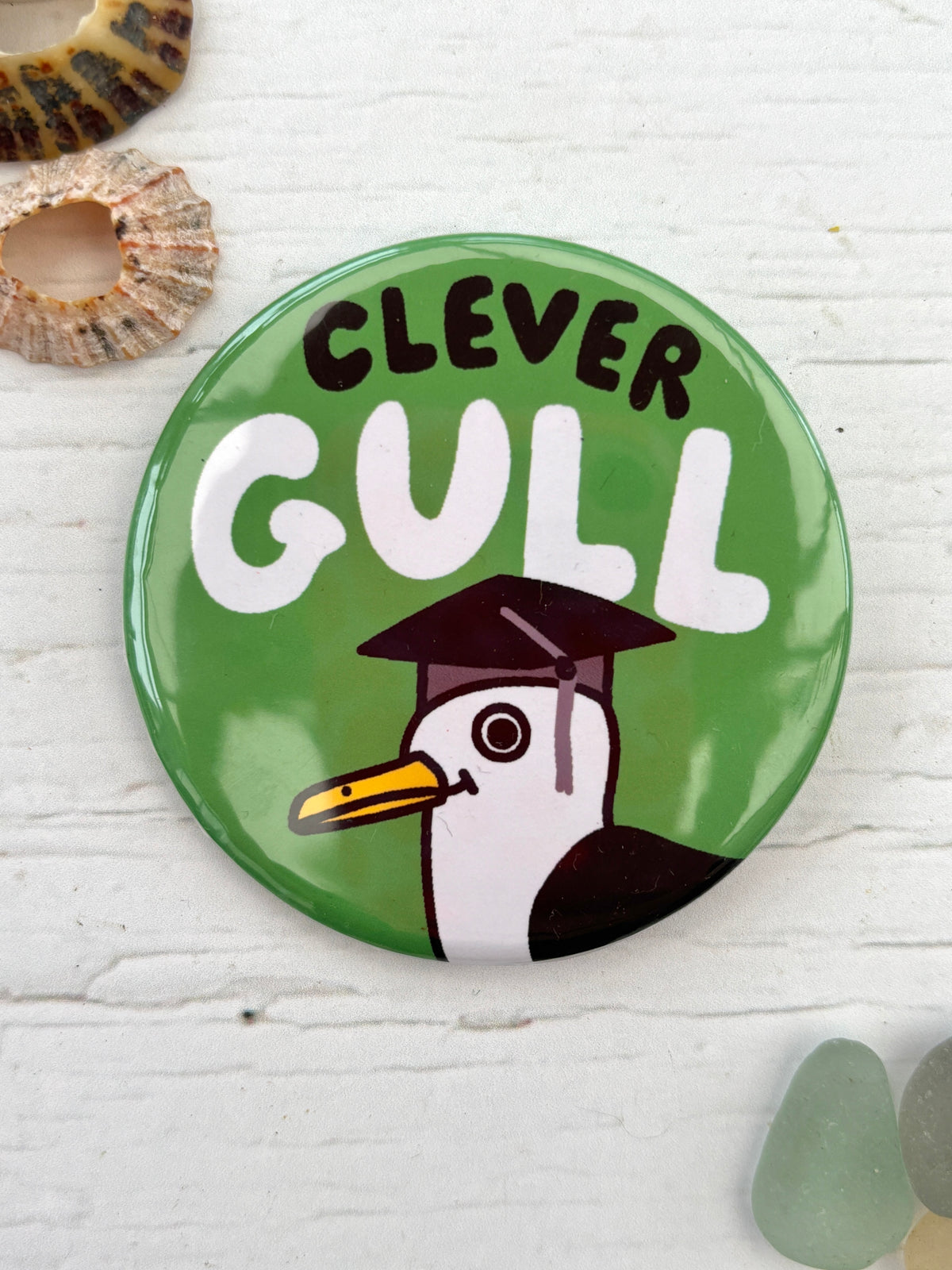 green seagull pin badge with the text 'Clever Gull' wearing a graduation hat funny novelty pin and coastal gift for graduates