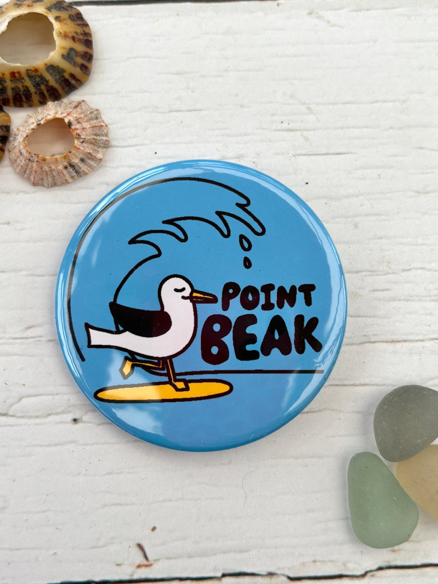blue seagull pin badge with the text 'Point Beak' showing a bird surfing funny nautical accessory, great coastal novelty gift for surfers