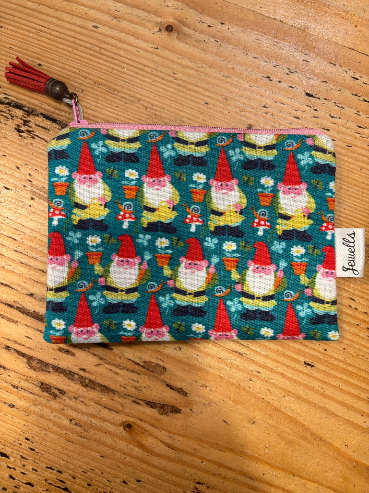 handmade fabric zipped purse with a fun, repeating garden gnome print on a teal background small coin pouch and quirky novelty gift with a tassel