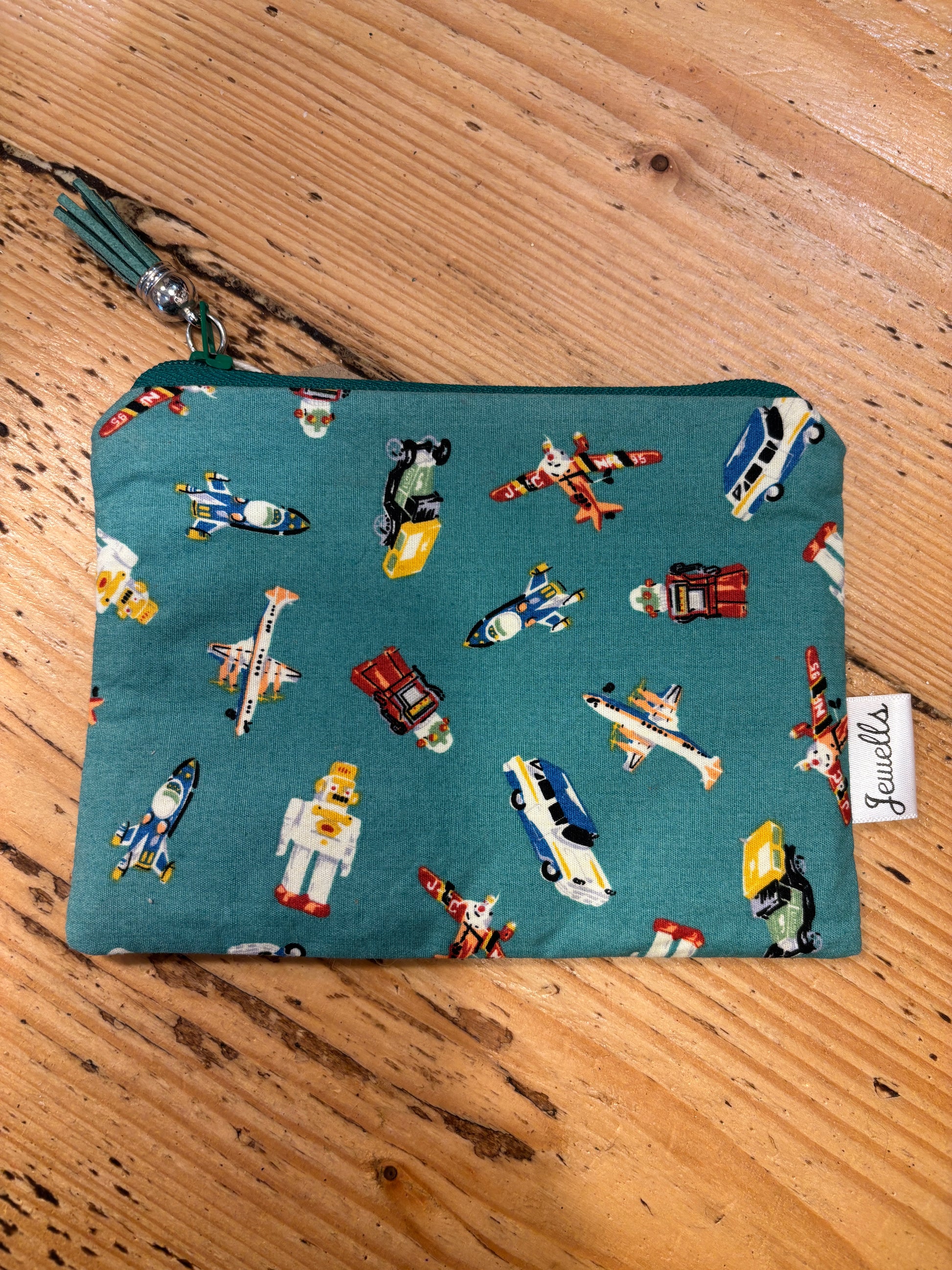 handmade fabric zipped purse with a fun retro print of planes, cars, and robots on a teal background small novelty gift with a tassel