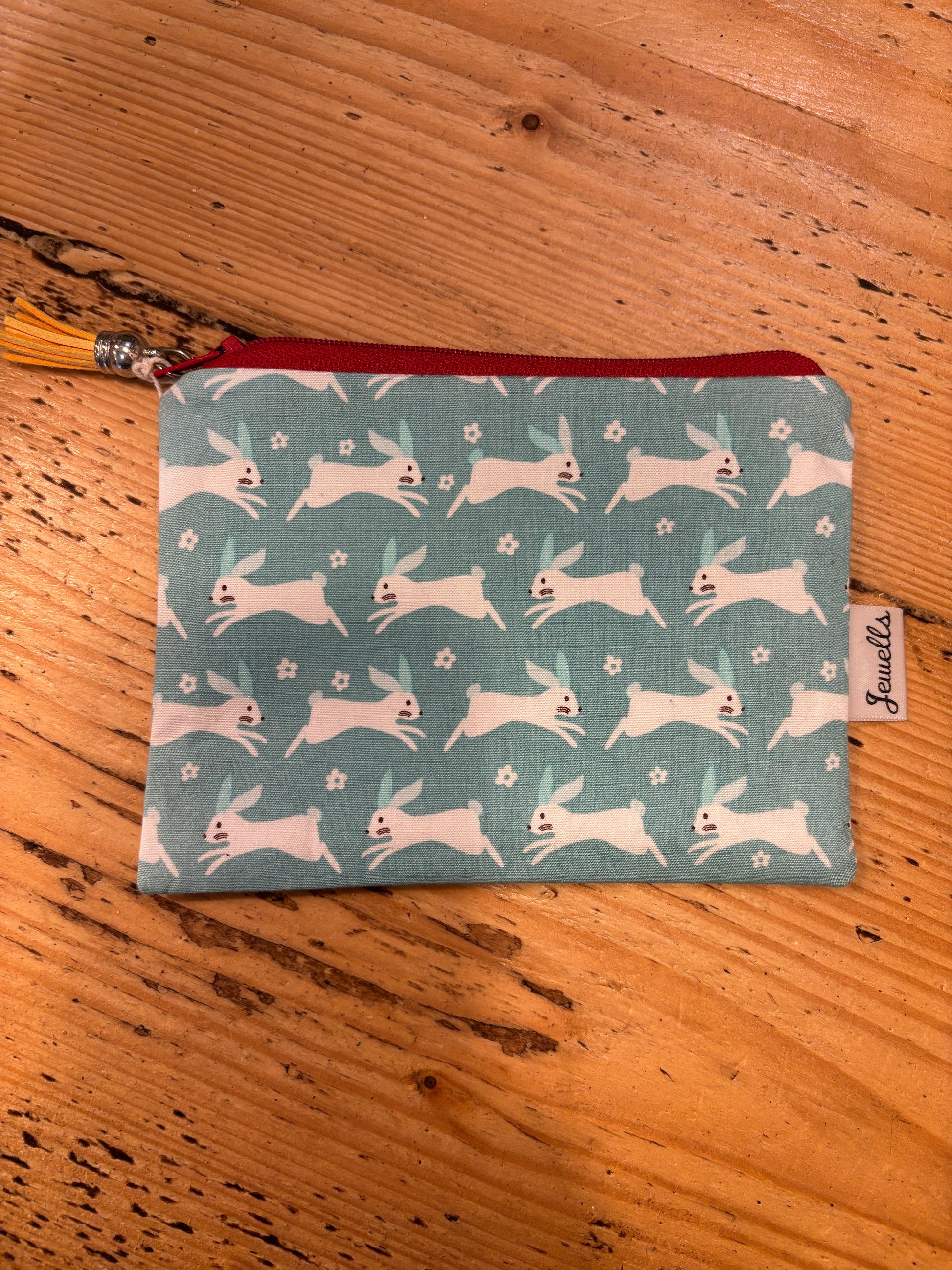 handmade fabric zipped purse with a white rabbit print on a pale blue background small coin pouch and unique gift accessory with a tassel