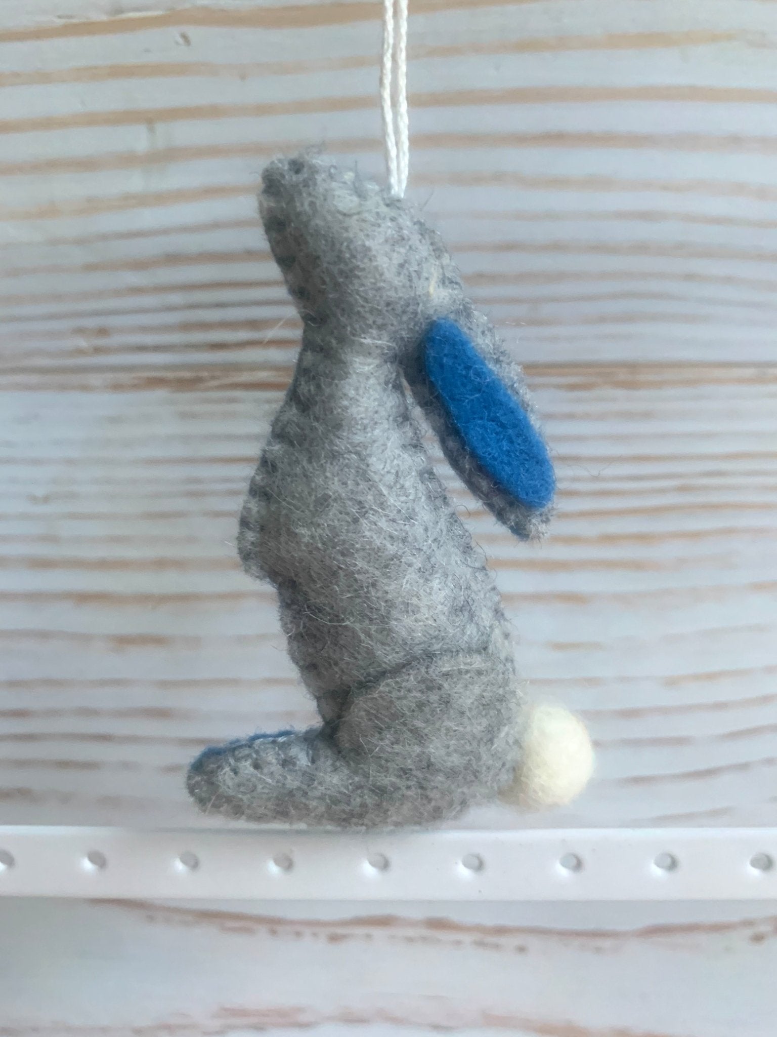 handmade grey felt Easter bunny decoration standing up, with a blue inner ear and fluffy white tail spring rabbit ornament and kids gift