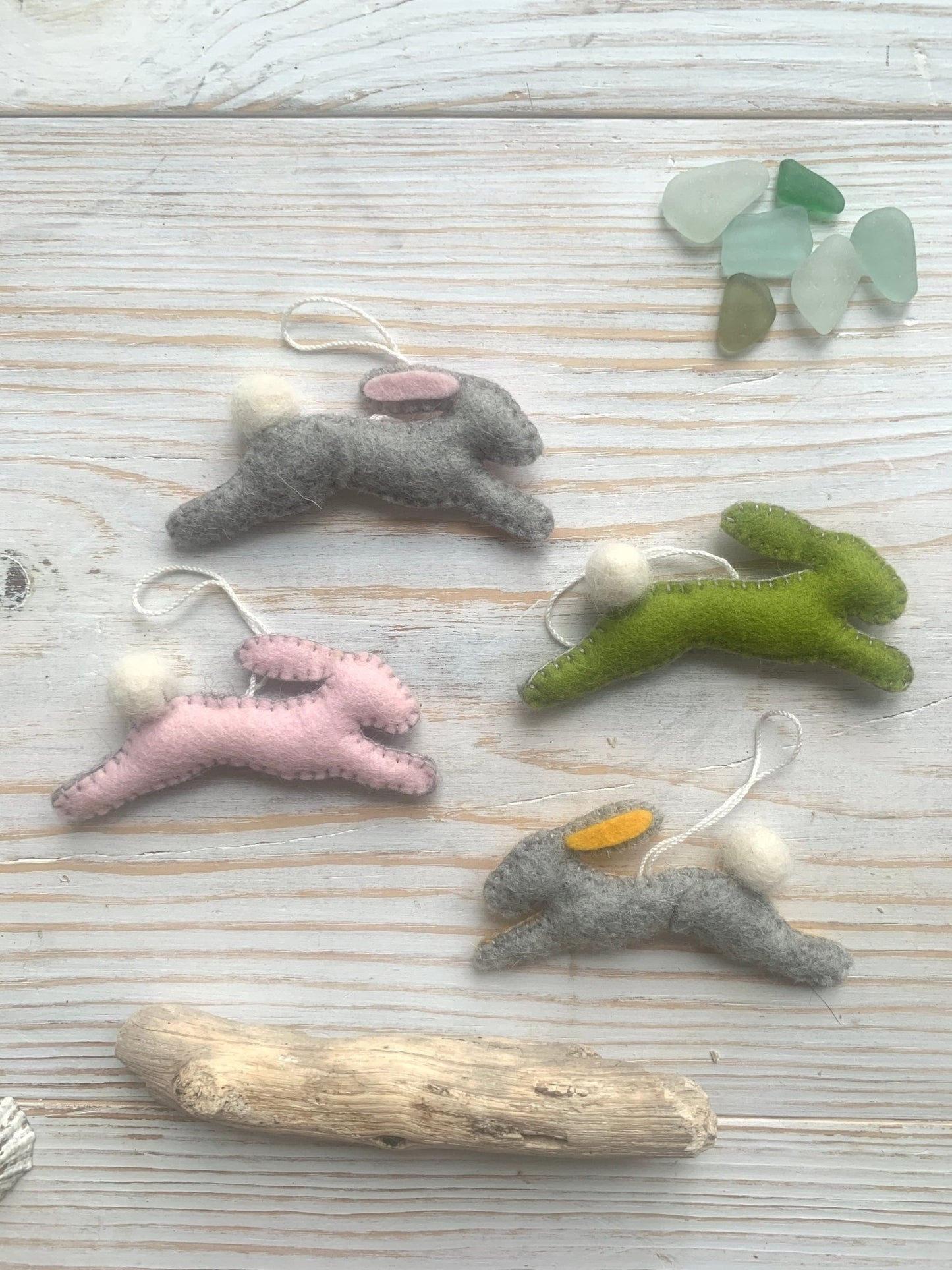 four handmade felt Easter bunny decorations in a leaping position (grey, pink, green) spring rabbit ornaments with fluffy pom-pom tails and colored ears easter decor gift