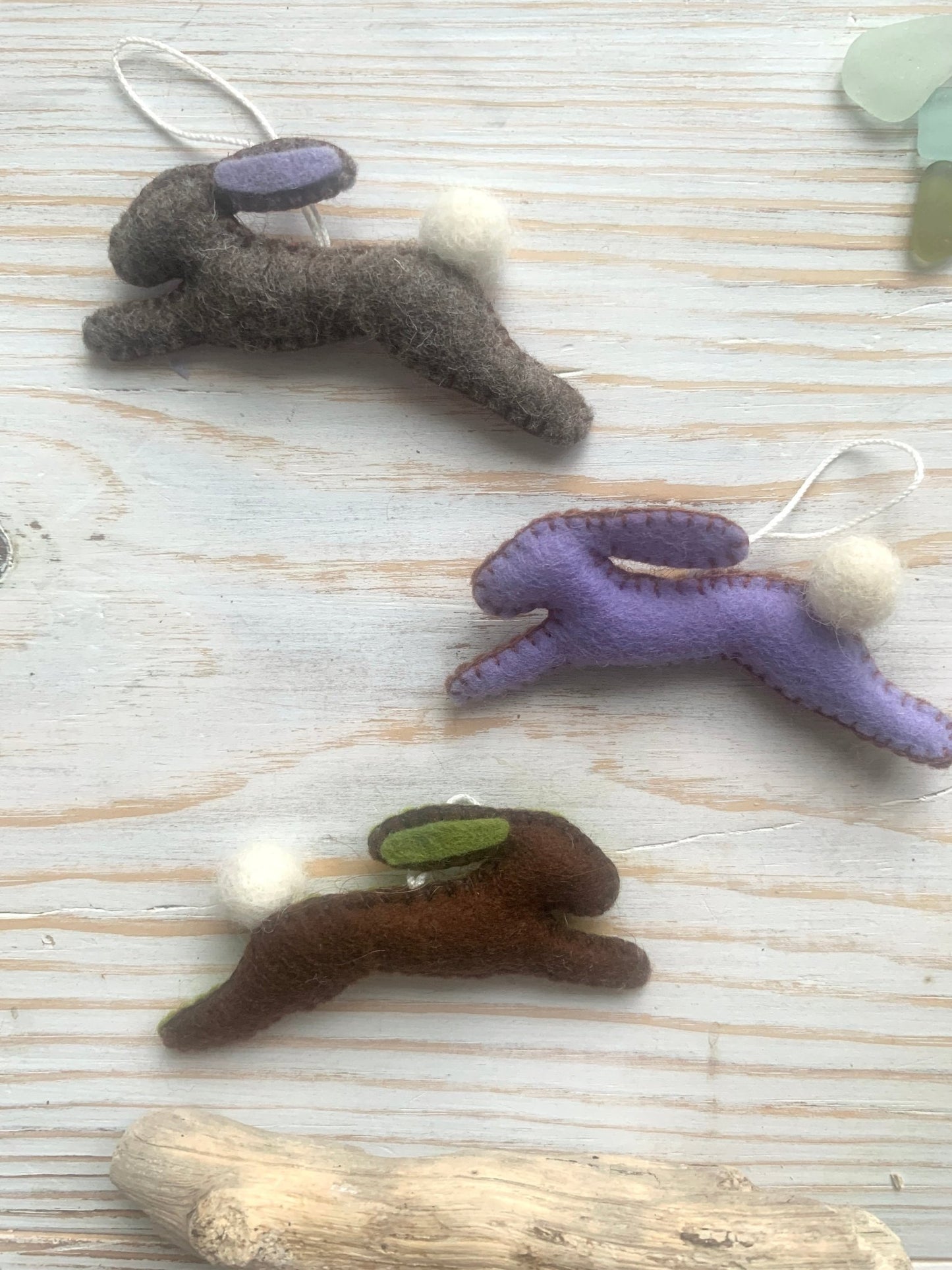 three handmade felt Easter bunny hanging decorations in leaping position (grey-brown, lilac, brown) spring rabbit ornaments with fluffy tails. Easter decor gift