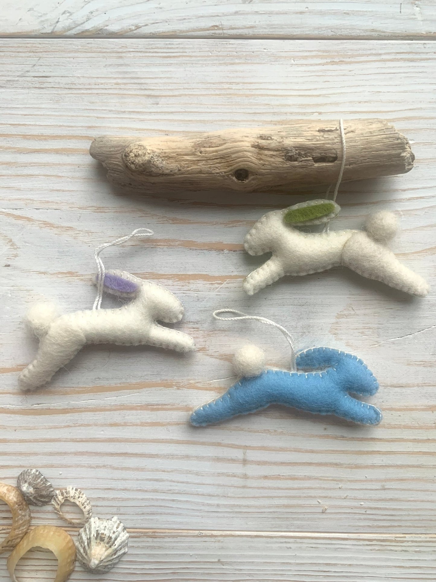 three handmade felt Easter bunny decorations in a leaping position (two white, one blue) spring rabbit ornaments with fluffy pom-pom tails easter decor gift