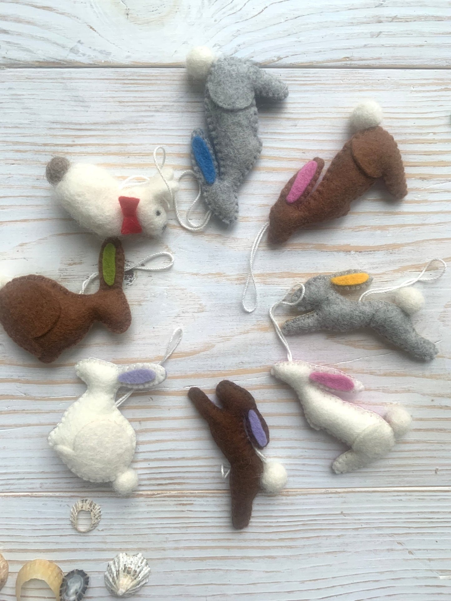 a collection of handmade felt Easter bunny decorations in various poses and colors spring rabbit ornaments with fluffy pom-pom tails easter decor gifts