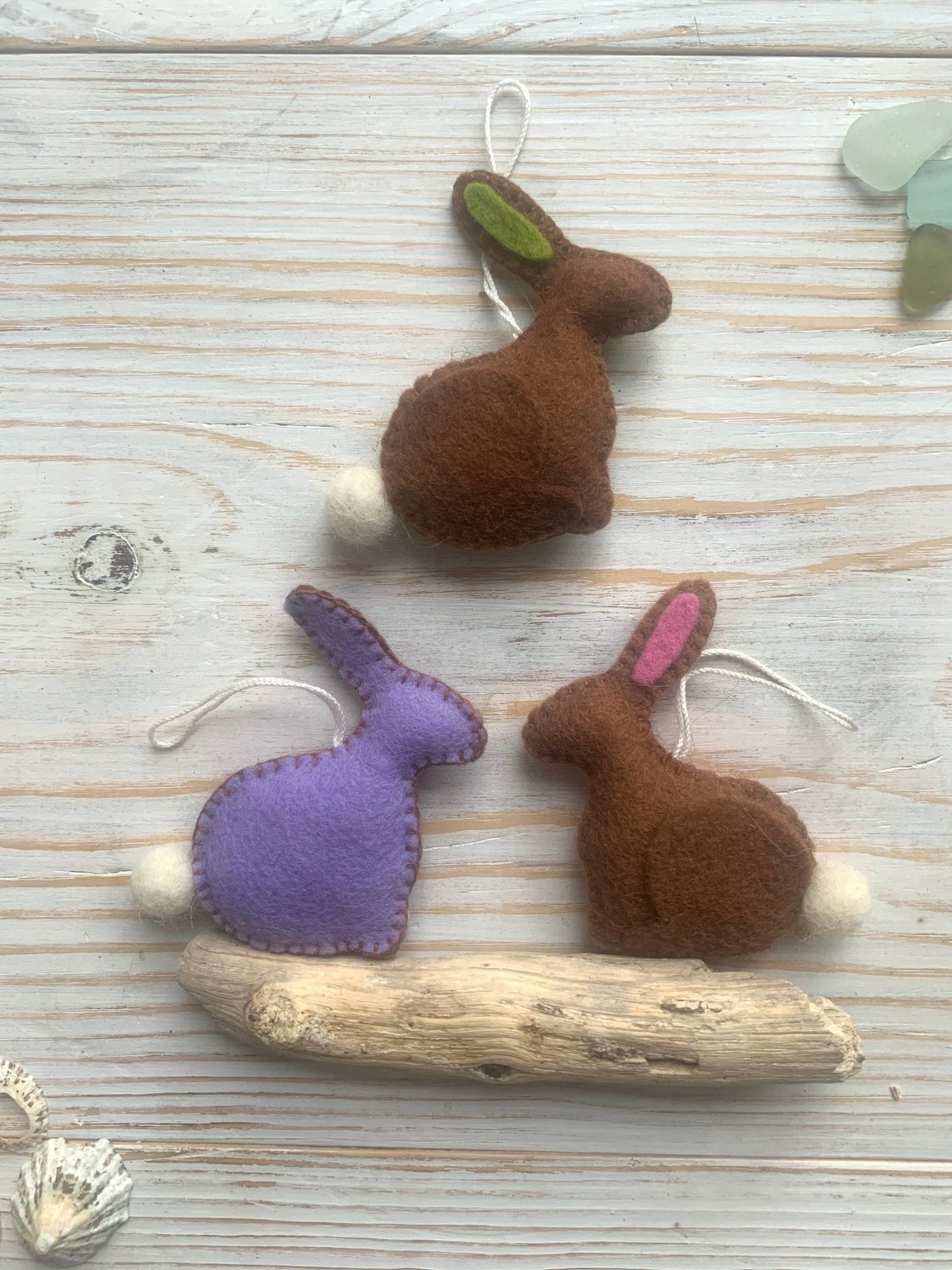 three handmade felt Easter bunny hanging decorations in brown and lilac spring rabbit ornaments with fluffy pom-pom tails easter decor or coastal gift