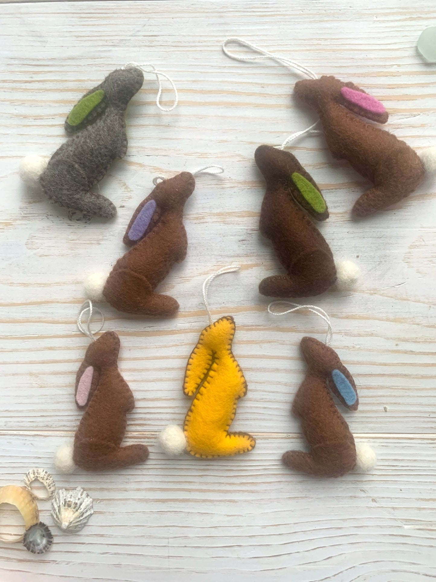 a collection of handmade felt Easter bunny decorations in a stargazing pose (brown, grey, yellow) spring rabbit ornaments with fluffy pom-pom tails easter decor gift
