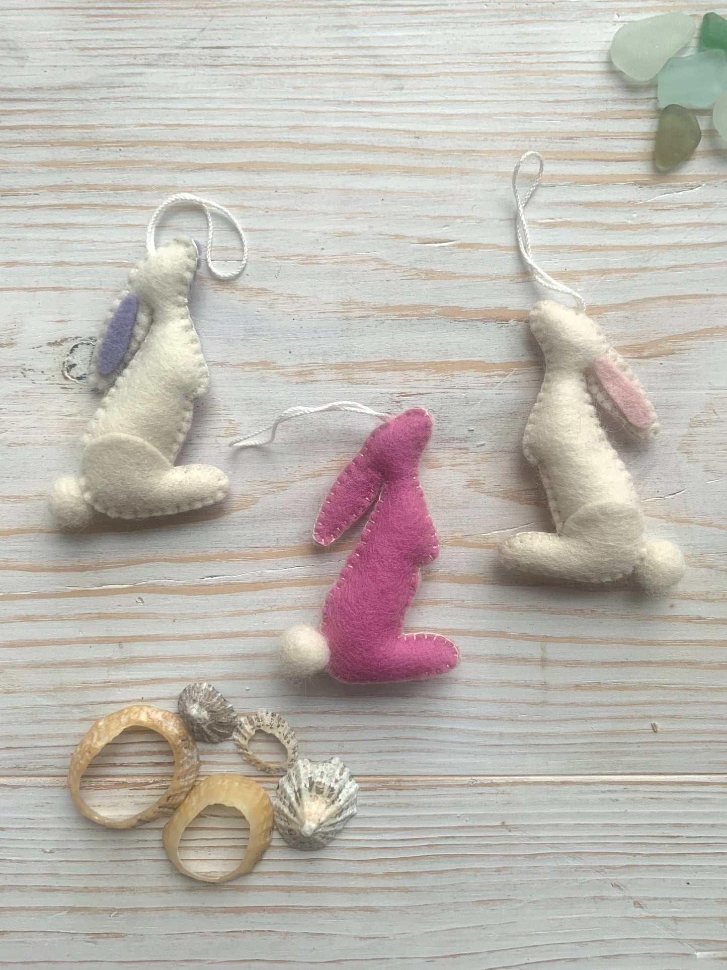 three handmade felt Easter bunny decorations in a stargazing position (white and pink) spring rabbit ornaments with fluffy pom-pom tails easter decor gift