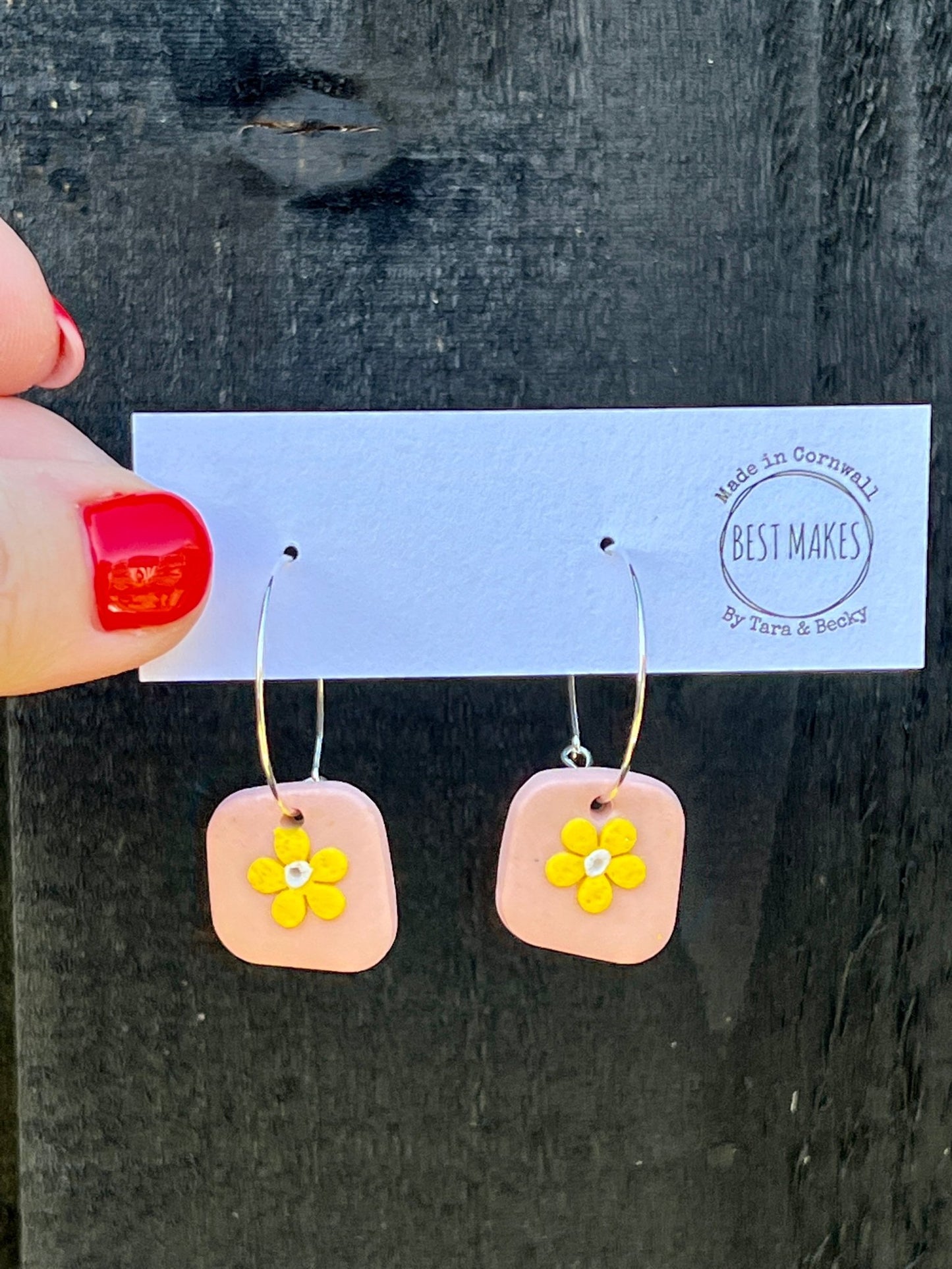 handmade daisy hoop earrings—pink square base with yellow flower charm, playful artisan gift from Cornwall