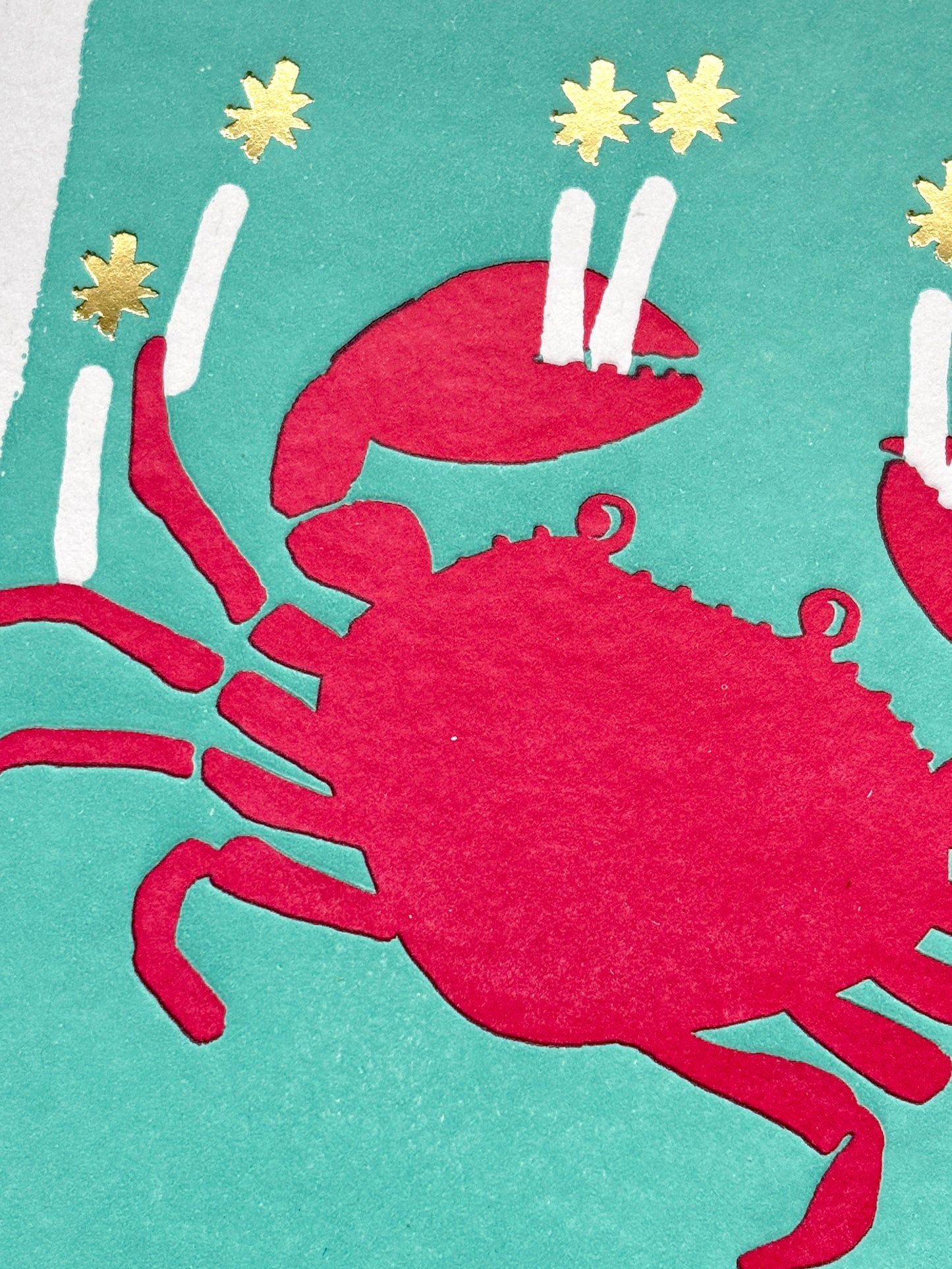 closeup shot of red crab birthday card with candle claws and gold stars on teal, perfect for ocean lovers and beachy celebrations