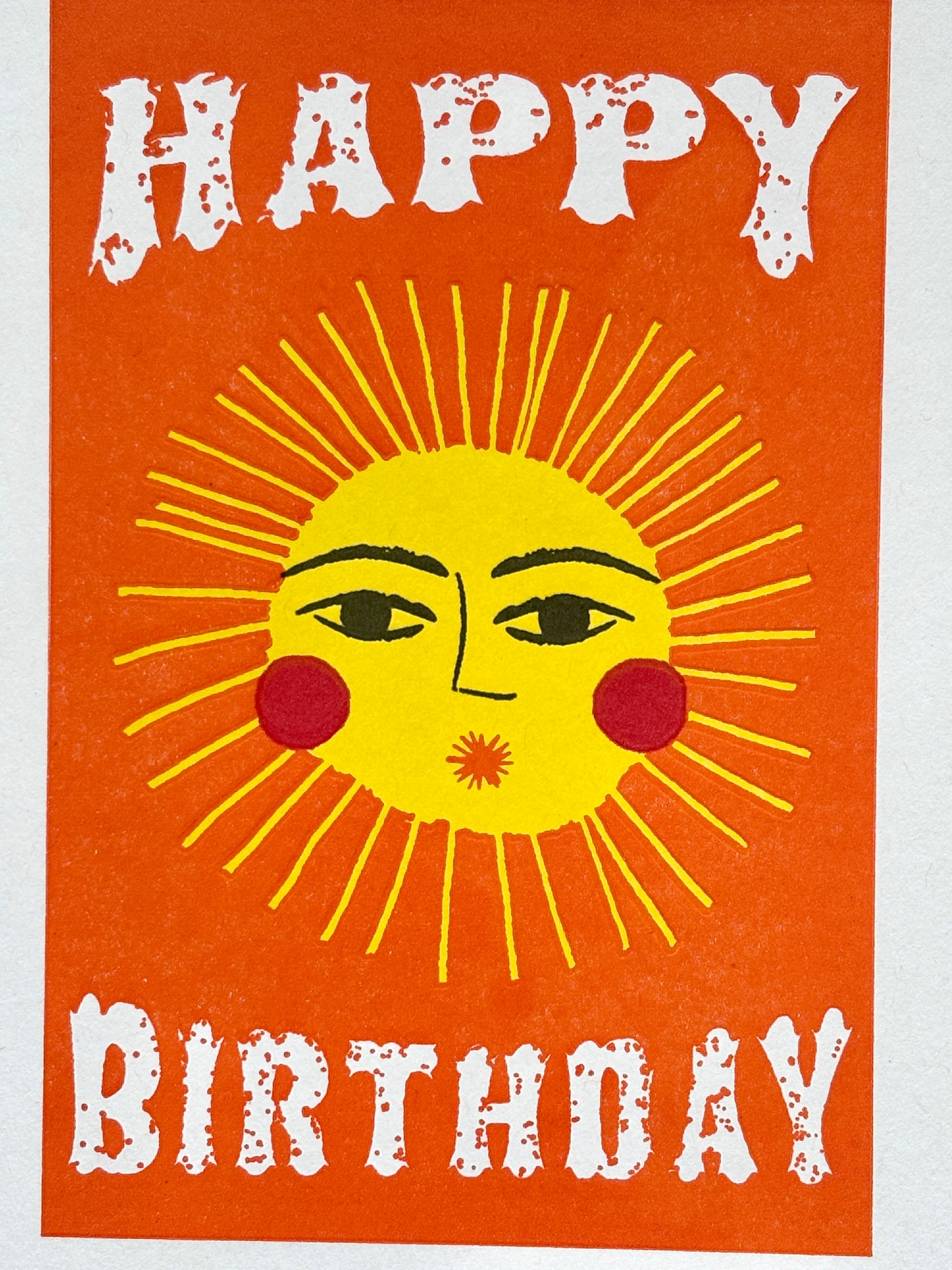 closeup shot of sunshine birthday card with bold sun face and white text on orange, perfect for cheerful coastal-themed gifting