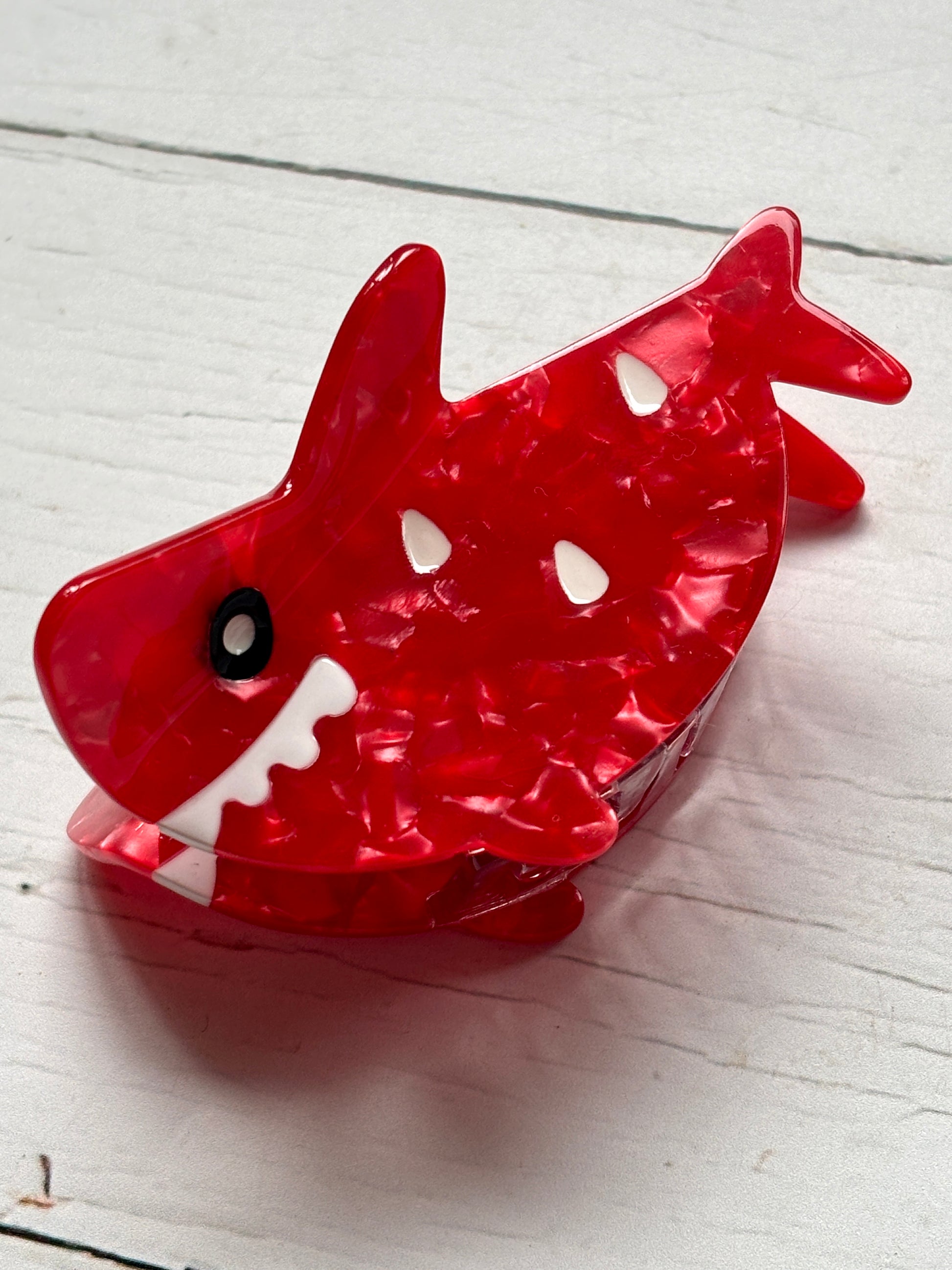 closeup shot of red shark hair claw—marbled texture, bold eye, toothy grin, and strong grip for playful everyday styling