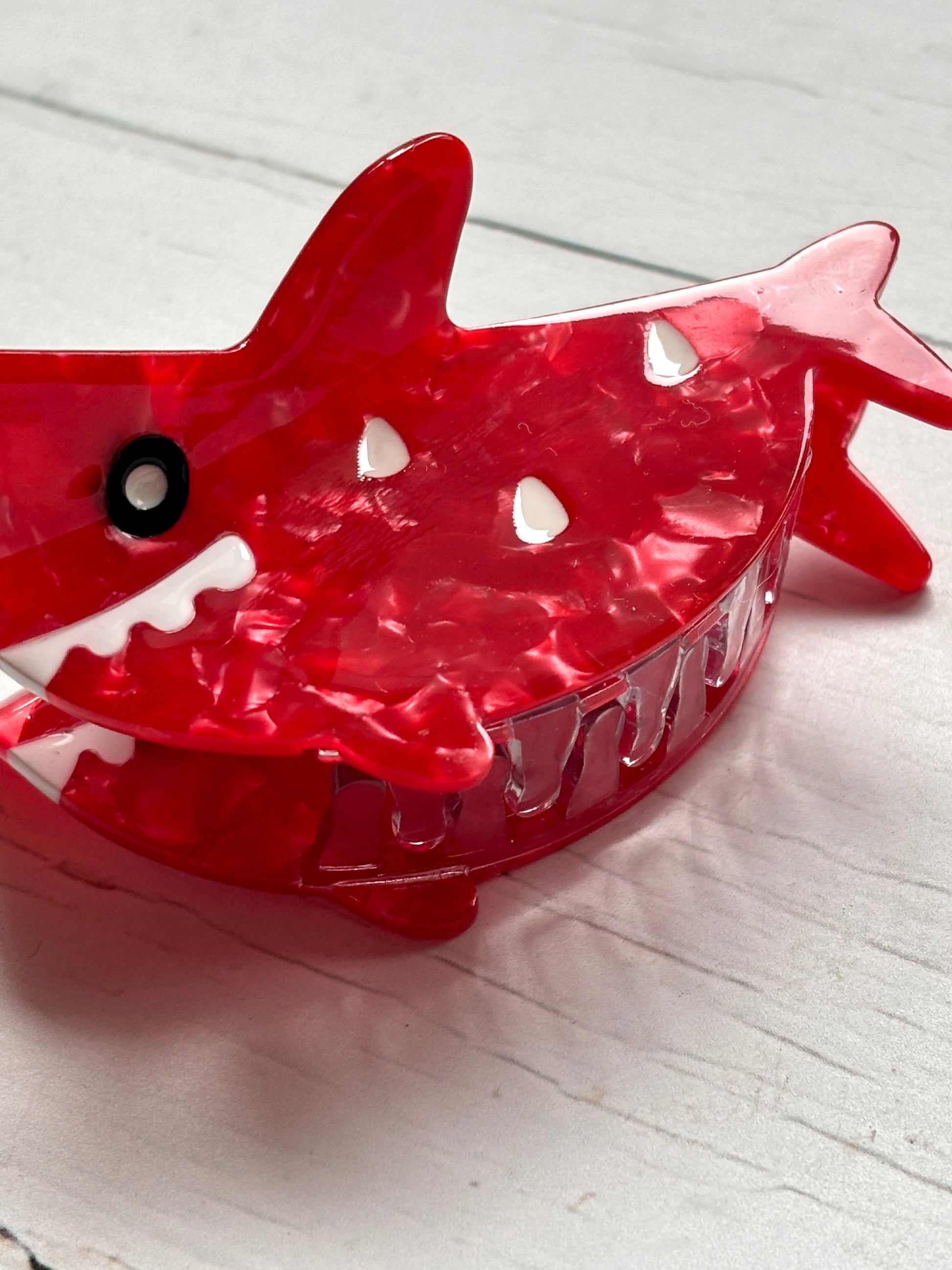 closeup shot of red shark hair claw—marbled texture, bold fins, cartoon teeth, and strong grip for playful styling
