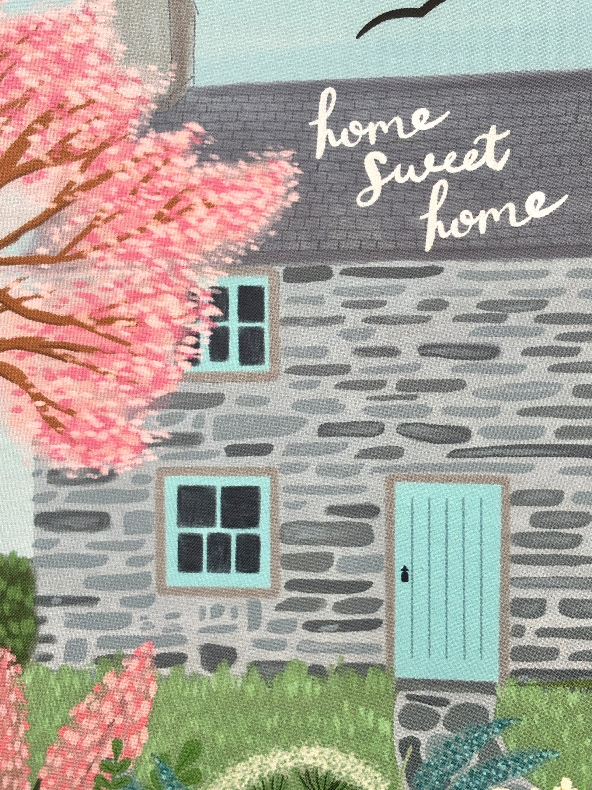 closeup shot of illustrated cottage card—“home sweet home” message, blooming garden, cozy countryside-themed stationery