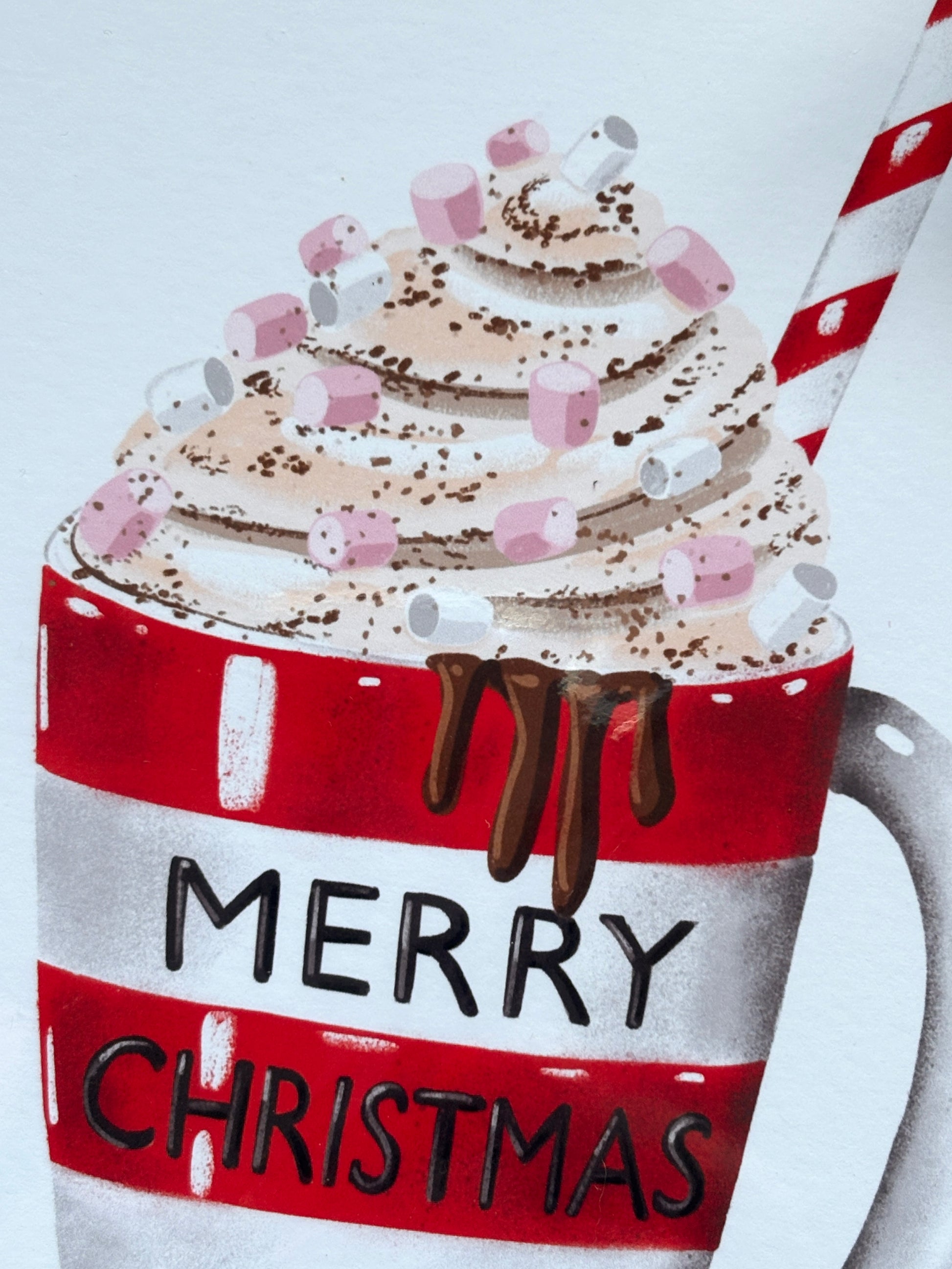 closeup shot of Christmas card with whipped cream hot chocolate, candy cane straw, marshmallows, and festive red striped mug design